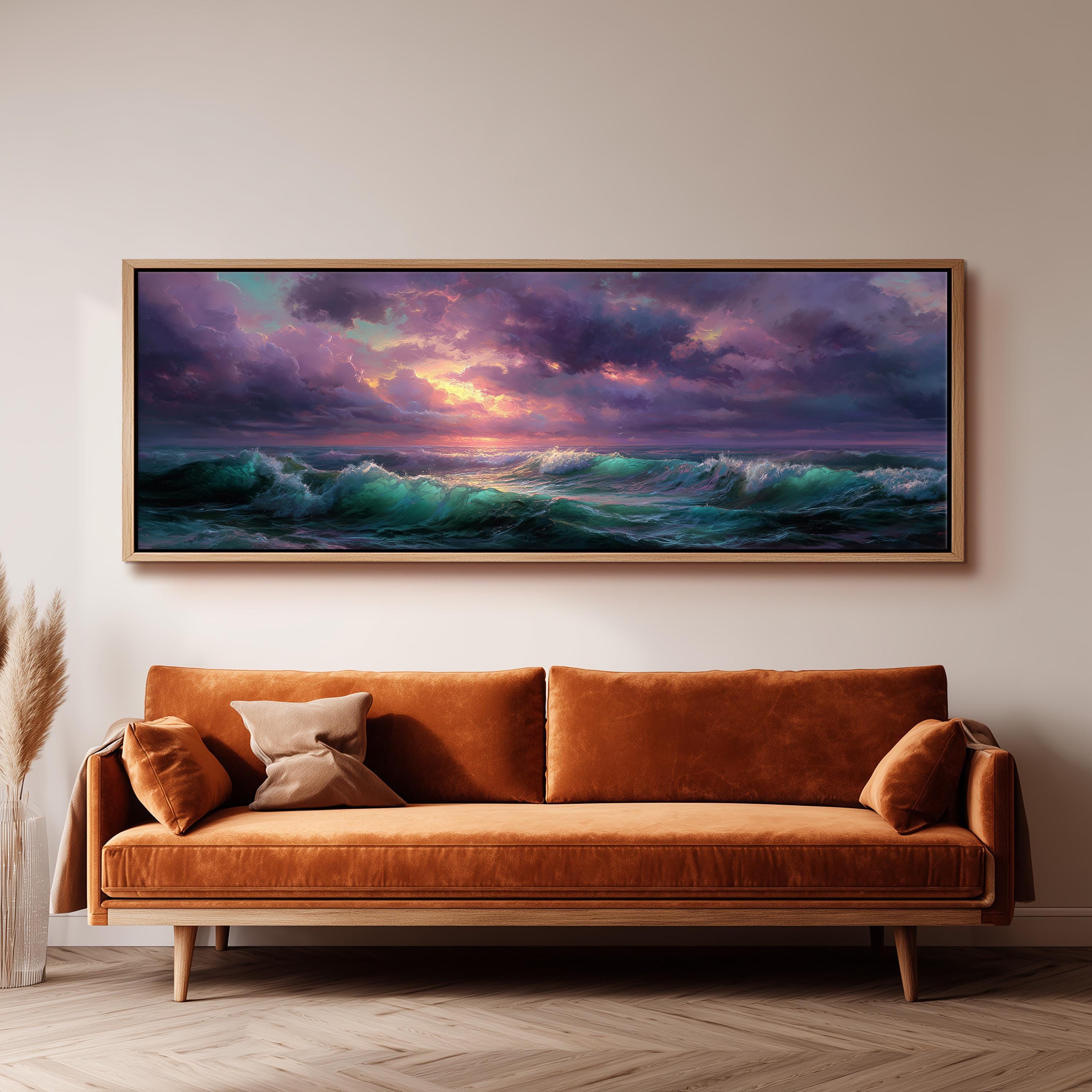 a large, framed painting of a serene ocean scene with a sunset over the waves. The painting is hanging on a wall above a brown sofa, creating a cozy and inviting atmosphere in the room.