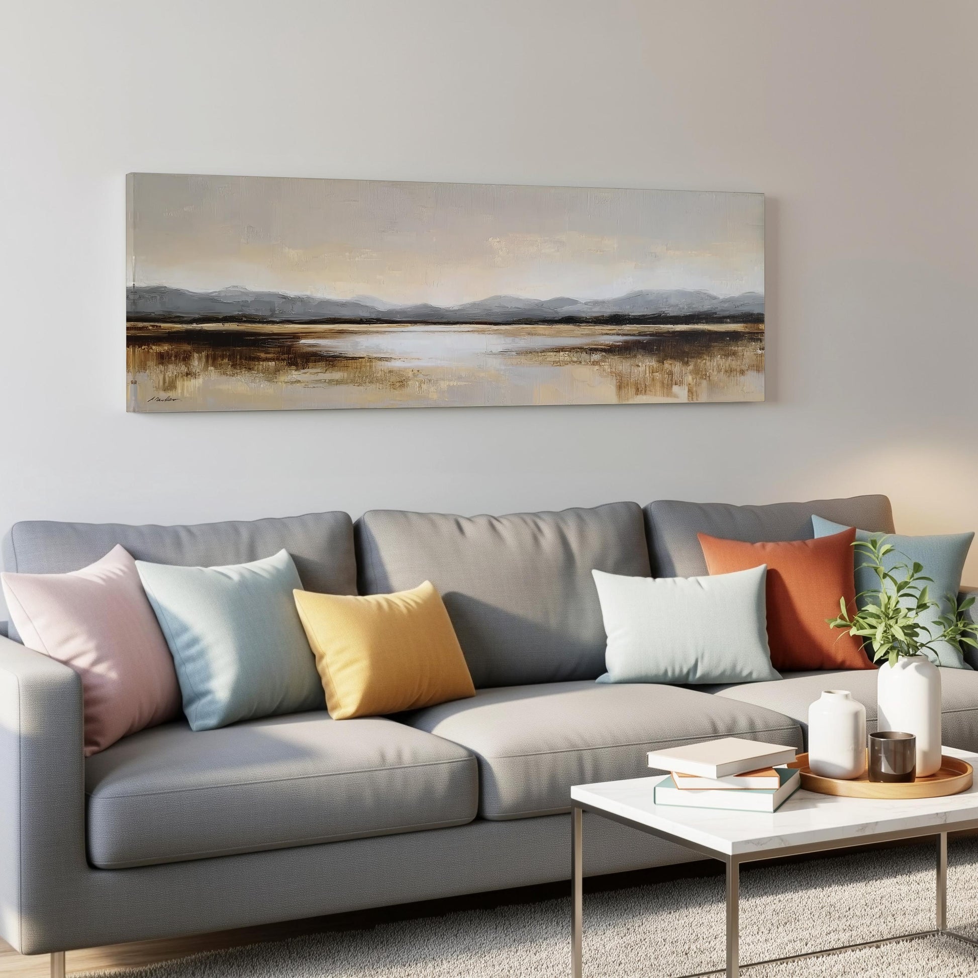 a modern living room with a gray sofa adorned with colorful throw pillows, a white coffee table, and a landscape painting hanging on the wall above the sofa.