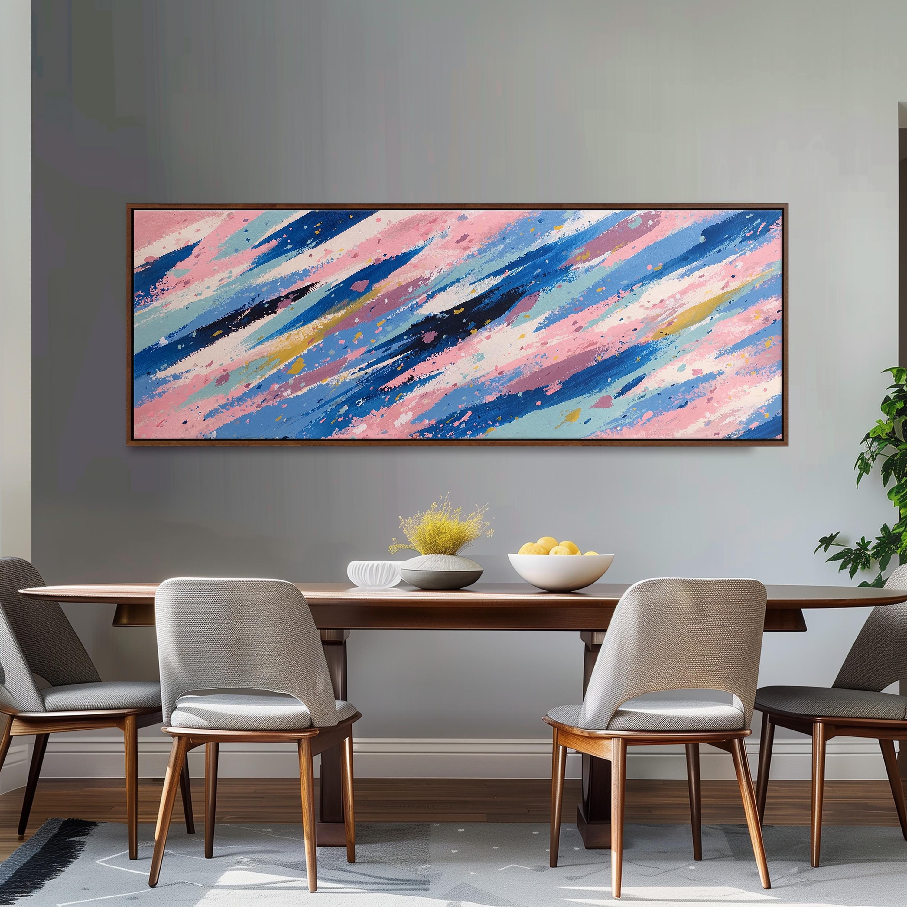 a dining room with a large abstract painting hanging on the wall above a wooden table with four chairs. The table is set with a bowl of fruit and a vase of flowers, creating a cozy and inviting atmosphere.