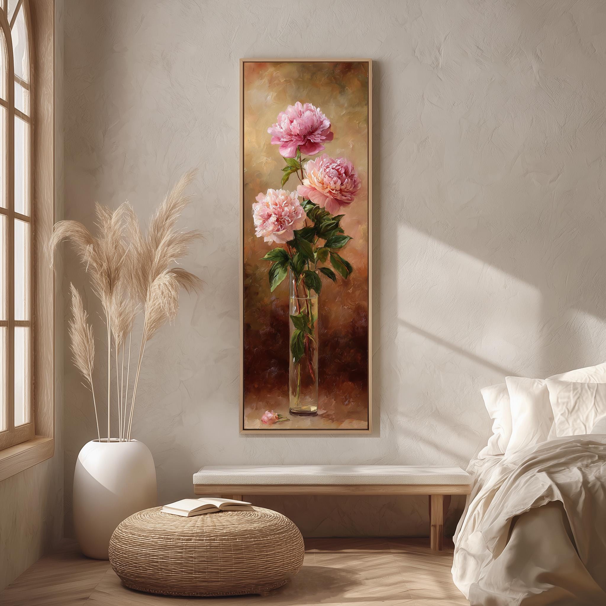 a large painting of pink flowers hanging on a wall, with a vase containing the flowers placed on a table in front of it. The painting is framed and appears to be a realistic representation of the flowers.