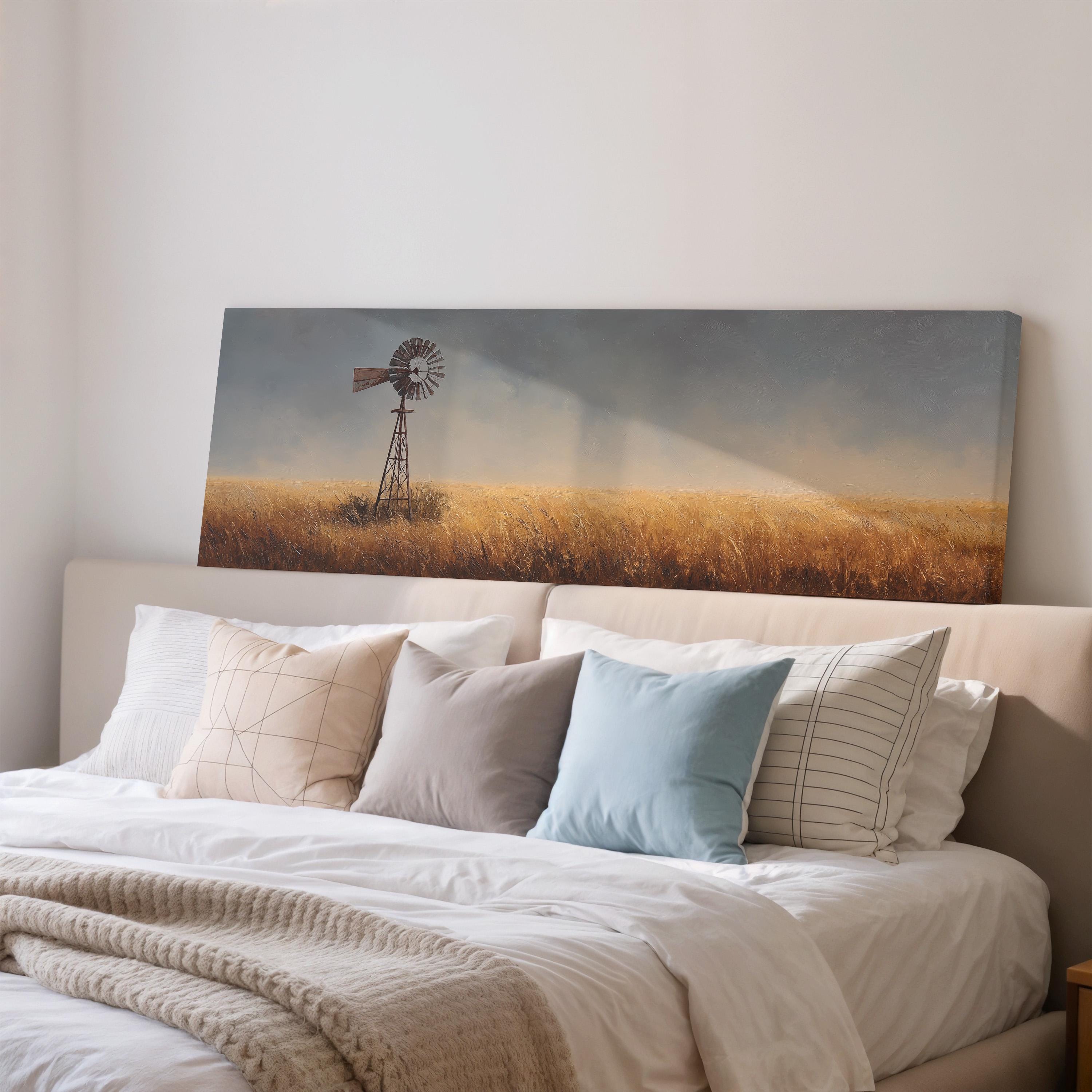 a large painting of a windmill on a wall above a bed with white pillows and a gray blanket.