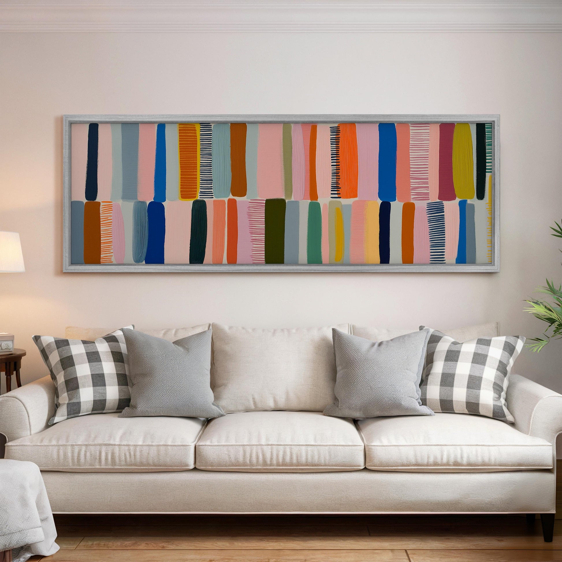 a large, colorful abstract painting hanging on a white wall above a white couch with gray and black plaid throw pillows.