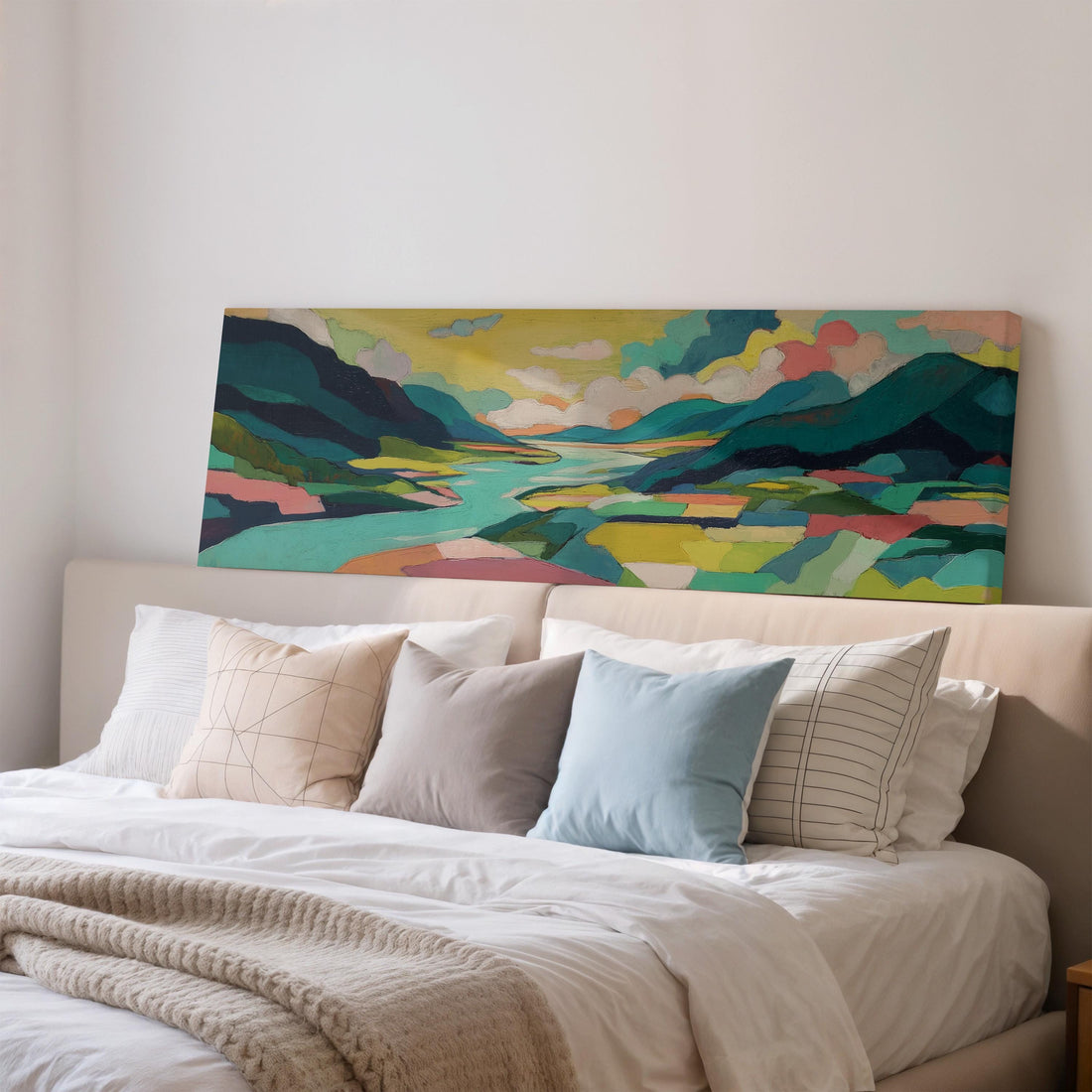 a large, colorful landscape painting hanging on a wall above a brown sofa with orange cushions.