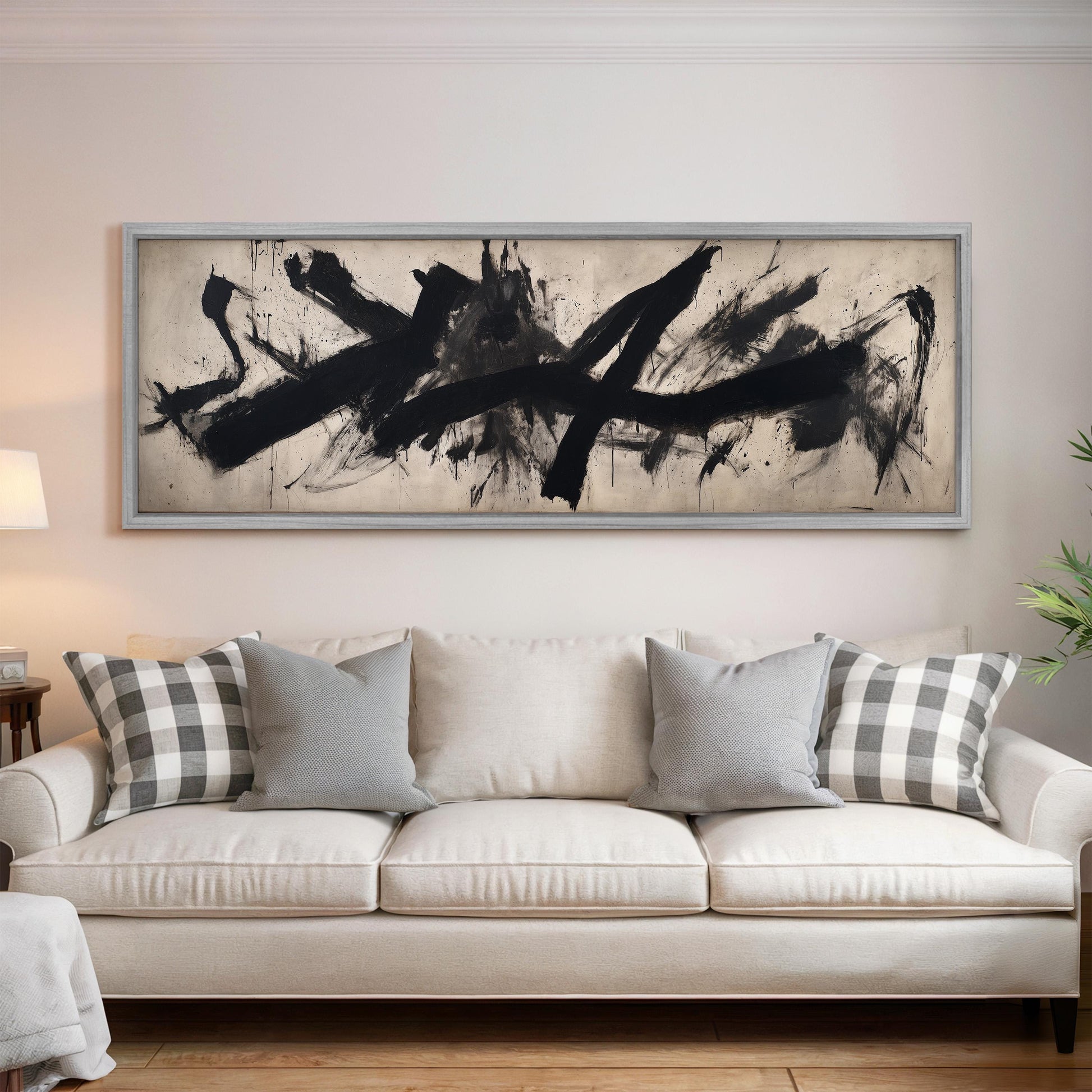 a large abstract painting hanging on a wall above a white sofa with gray and white plaid throw pillows.