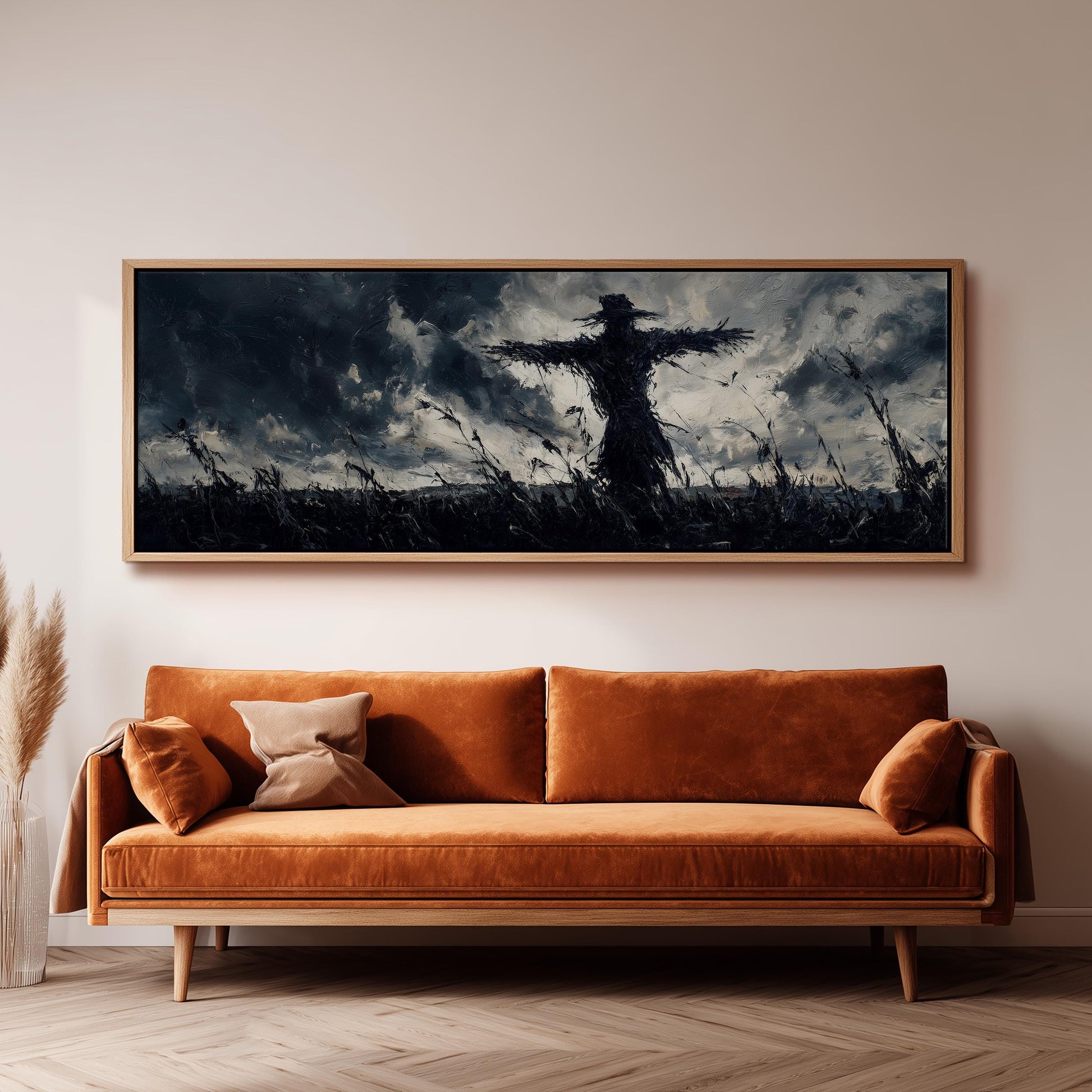 a large, dark-toned painting of a scarecrow in a field, hanging on a wall above a brown sofa.