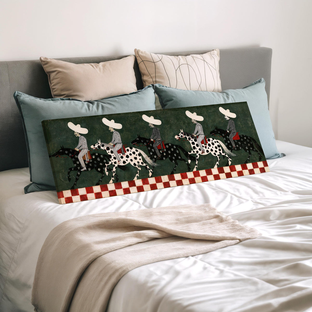 Riders in sombreros on spotted horses wide panoramic canvas print laid on a bed to show its size