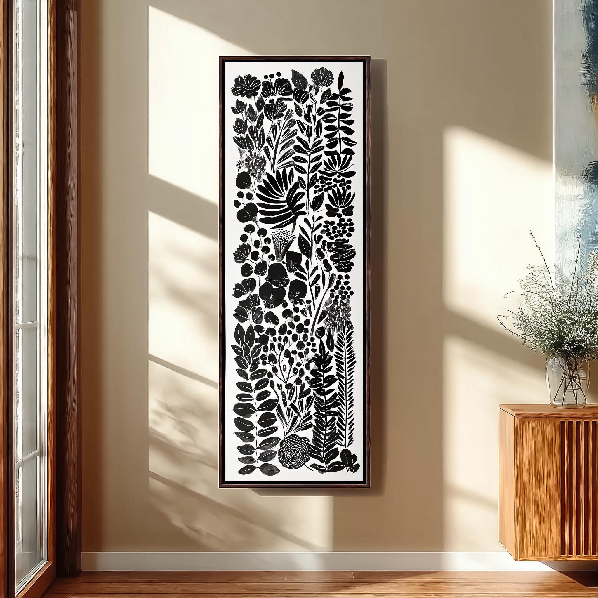 a large black and white framed artwork hanging on a wall, depicting a variety of plants and leaves.