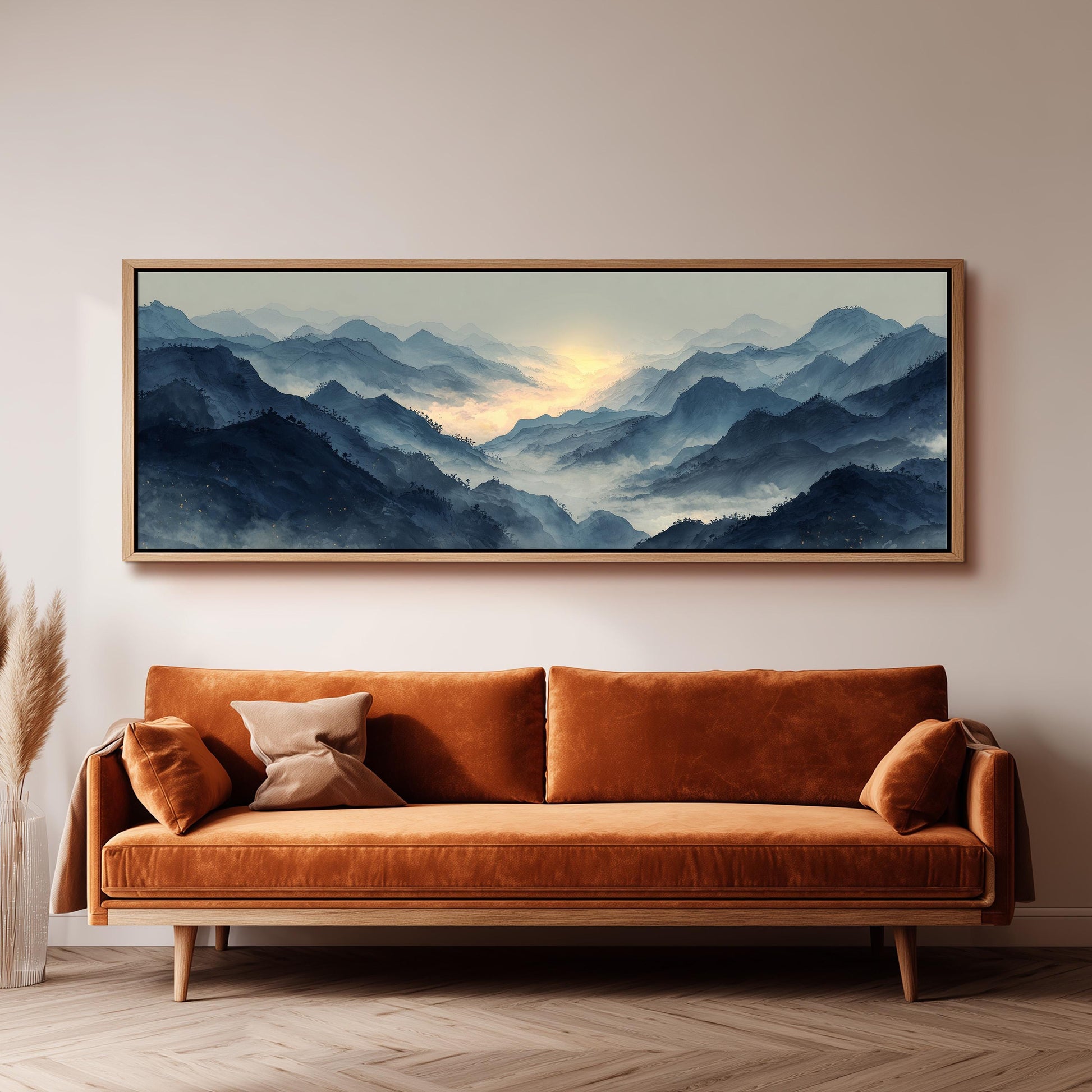 a large, framed painting of a mountainous landscape hanging on a wall above a brown sofa.