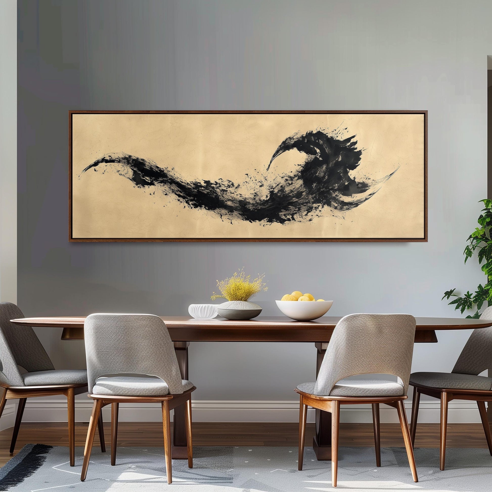 a dining room with a wooden table and four chairs. Above the table, there is a large black and white abstract painting hanging on the wall. The table is set with a bowl of fruit and a vase of flowers, creating a cozy and inviting atmosphere.