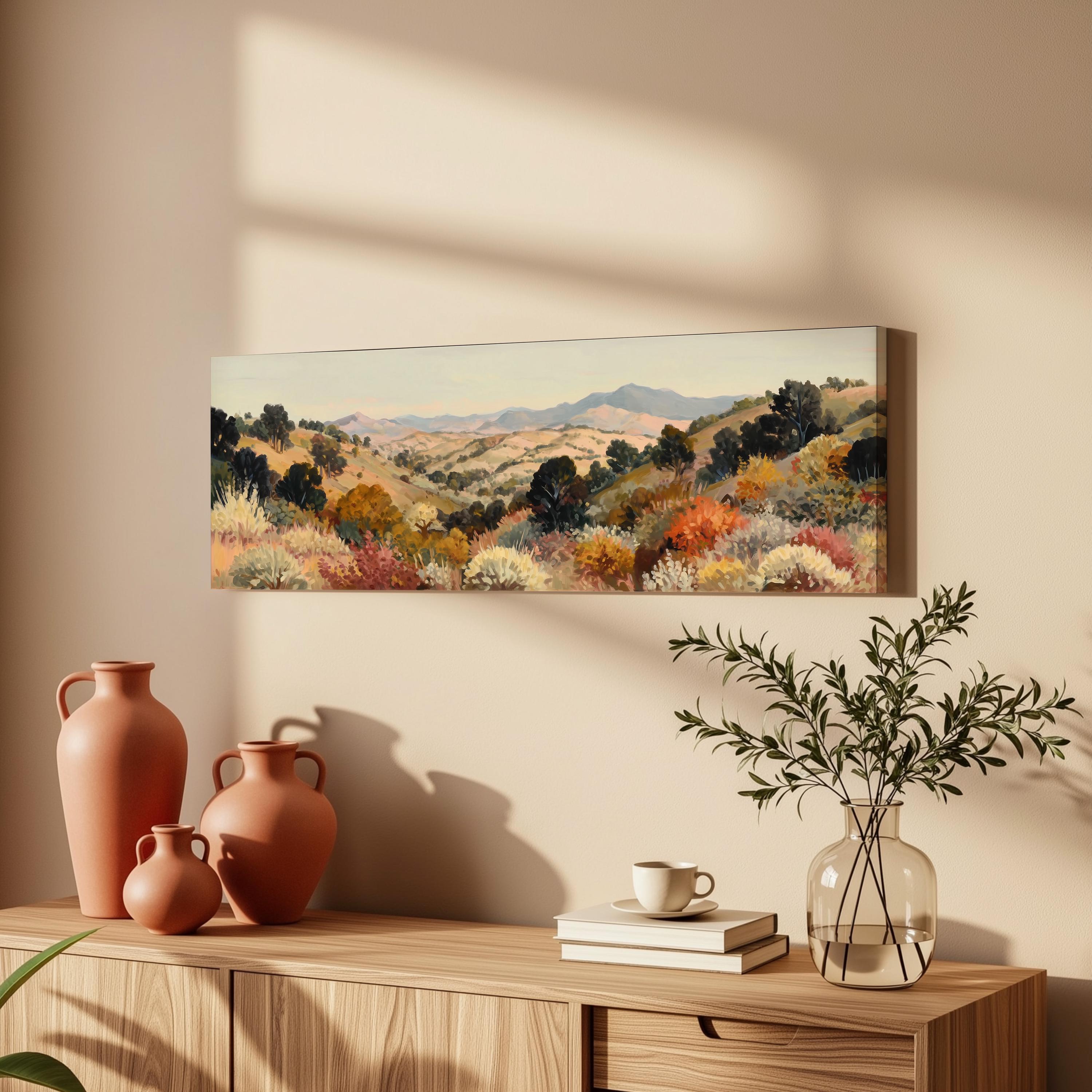 a wooden cabinet with a painting of a desert landscape hanging on the wall above it. The cabinet also has three orange vases and a glass vase with greenery on top of it.