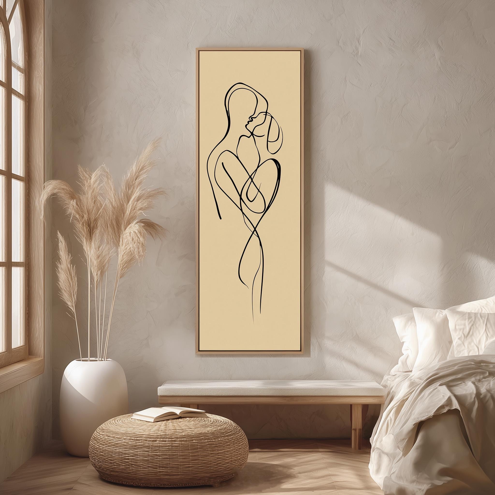 a minimalist bedroom setting with a large abstract drawing of a couple embracing on the wall, a white bed with a white pillow, a white vase with potted plants, and a woven ottoman.