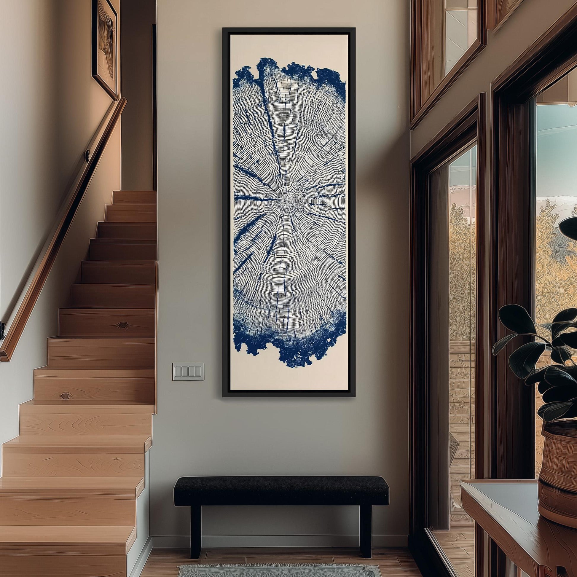 a hallway with a large tree trunk print artwork hanging on the wall, a wooden staircase, a black bench, and a potted plant.