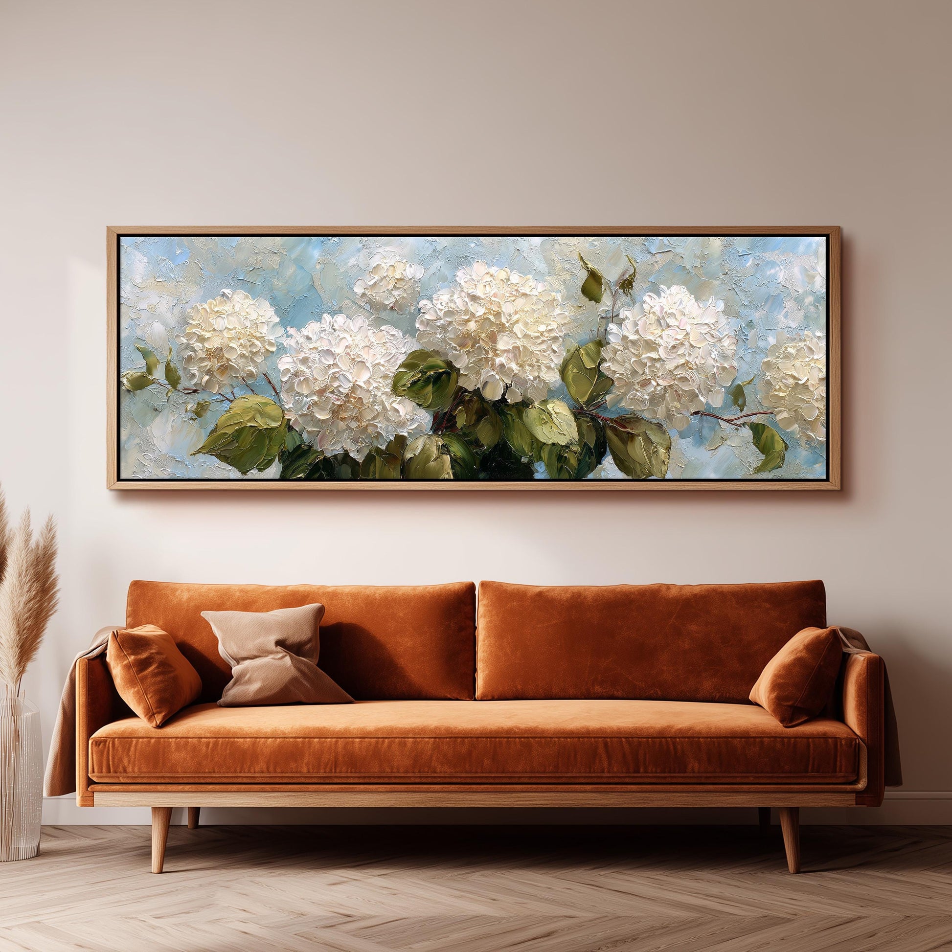a large painting of white hydrangeas hanging on a wall above a brown sofa.