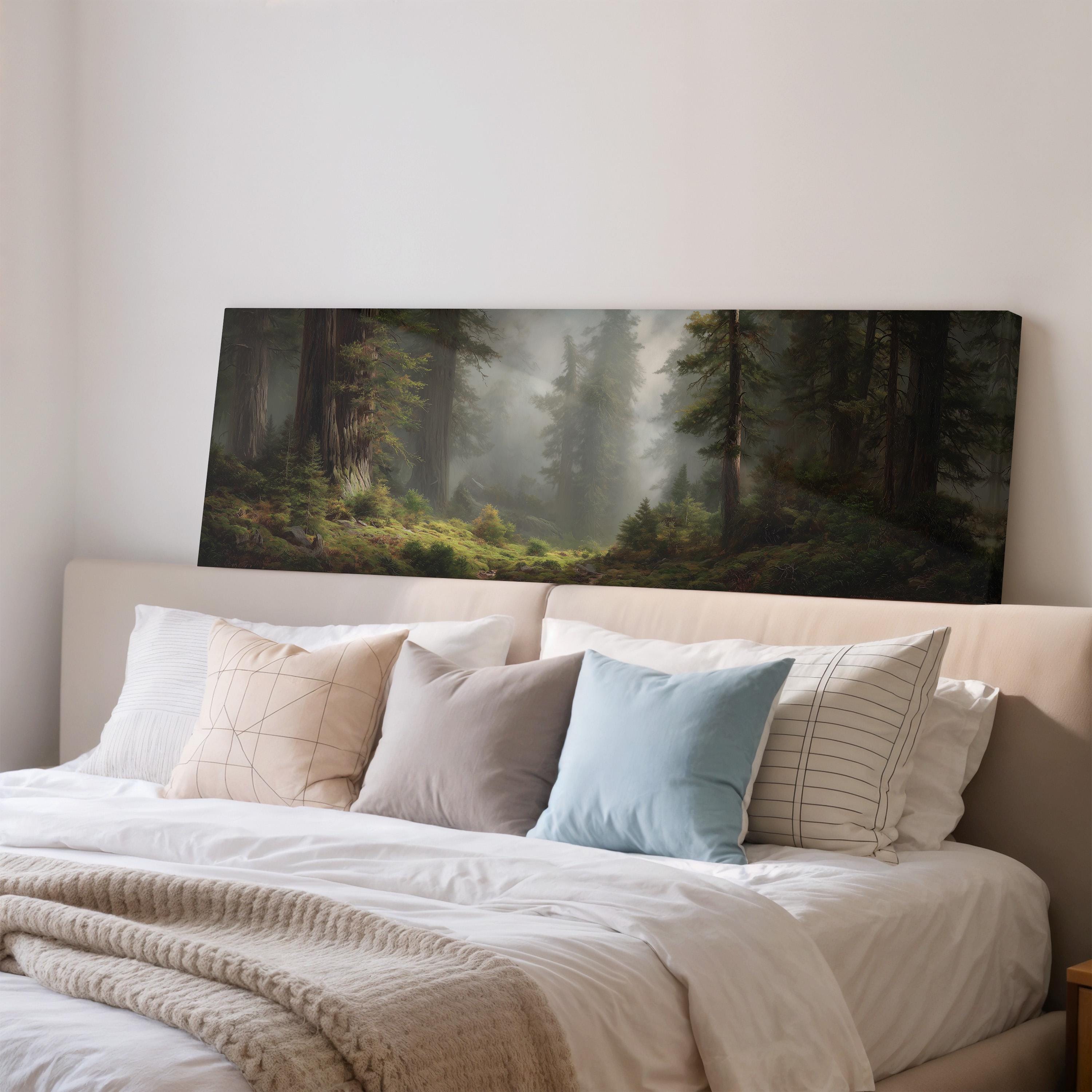 a large painting of a forest scene hanging on a wall above a bed with white bedding and pillows.