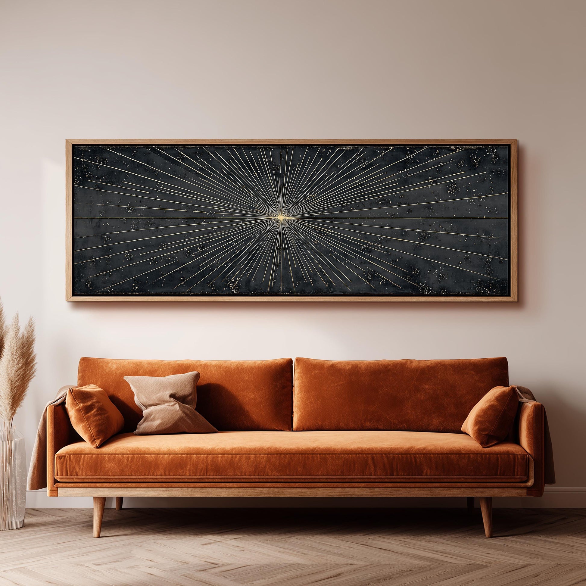 a large, rectangular black and gold artwork hanging on a white wall above a brown sofa with orange cushions.