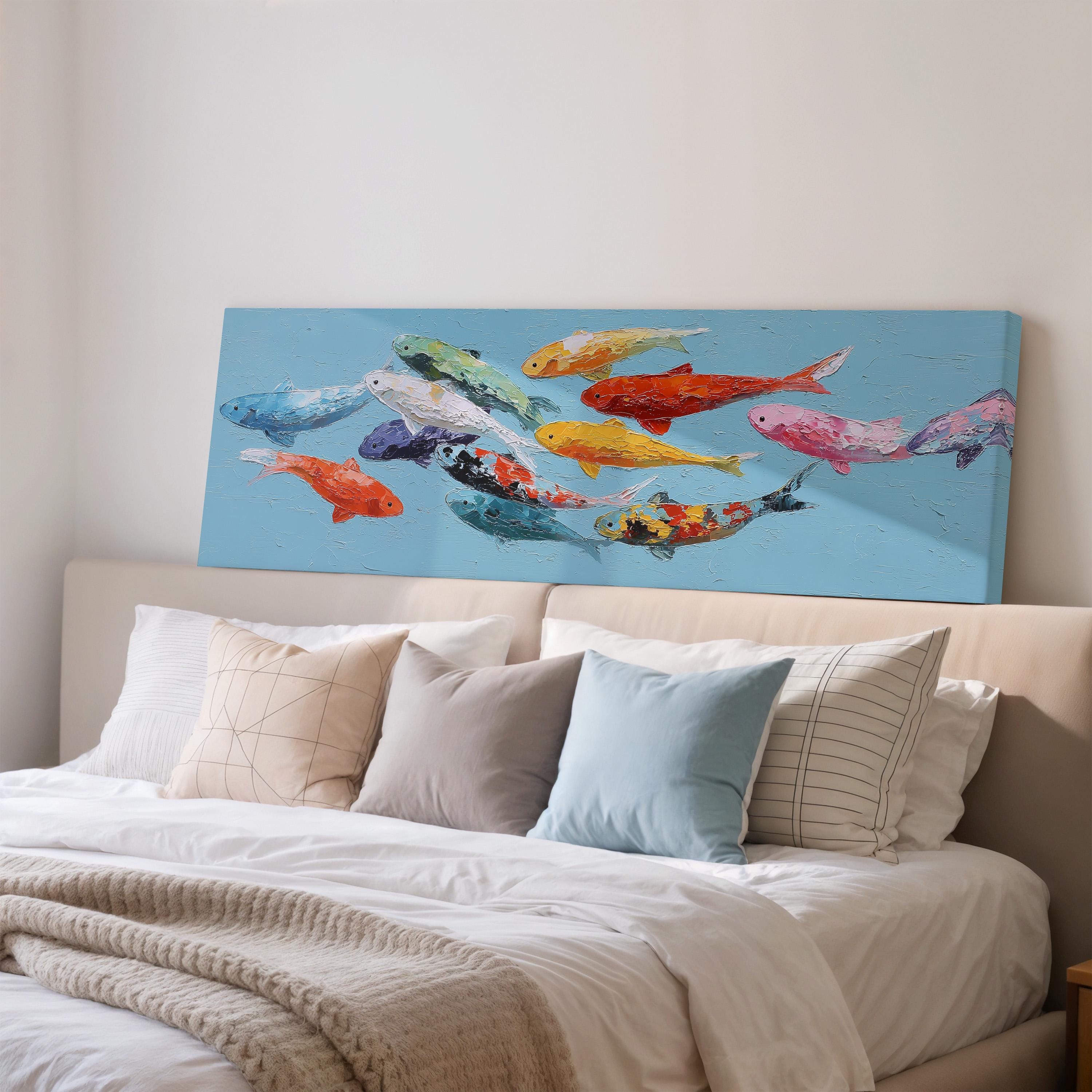 a large blue canvas with a painting of colorful fish on it, displayed above a bed with white pillows and a gray blanket.