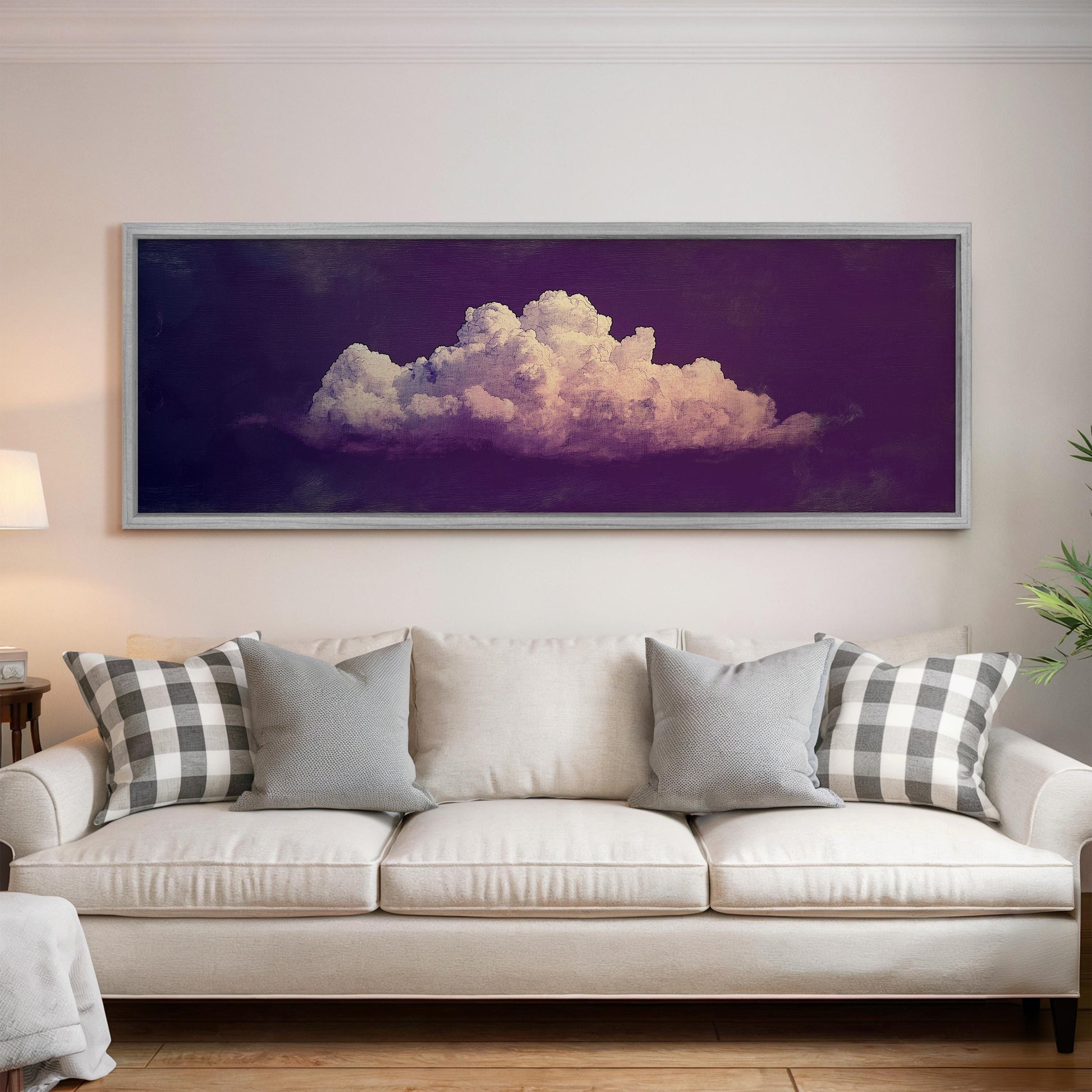 a large framed picture of a cloud hanging on a wall above a white couch with gray and white pillows.
