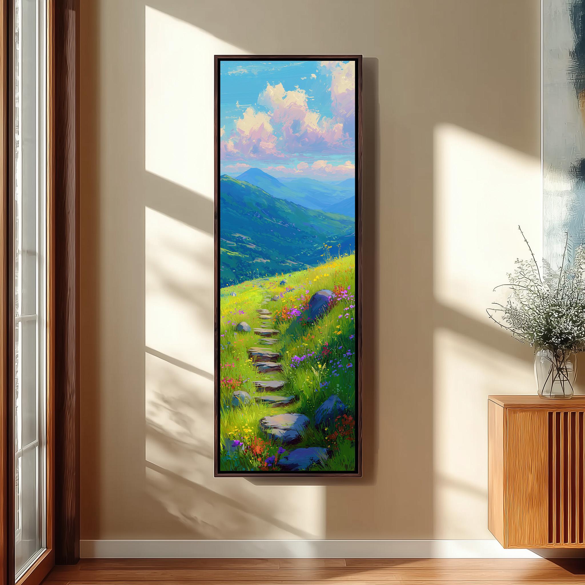 a large, framed painting hanging on a wall, depicting a scenic mountain landscape with a winding path leading through a grassy field dotted with flowers.