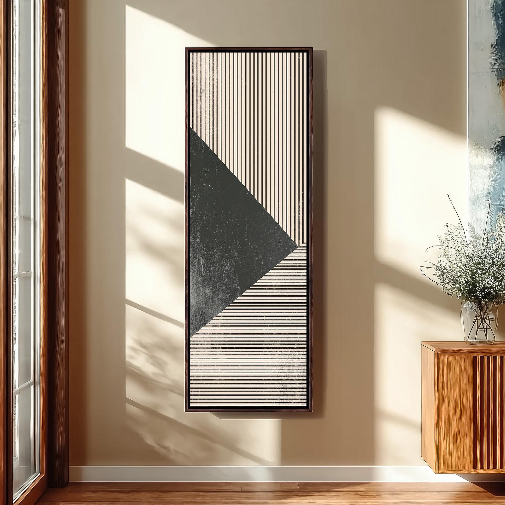 a minimalist art piece with a black and white geometric design on a wall, accompanied by a wooden cabinet and a vase of flowers.