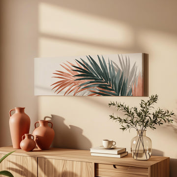 a wooden cabinet with a vase of greenery, a coffee cup, and a stack of books on top. Above the cabinet, there is a framed artwork depicting palm leaves in shades of green and orange.