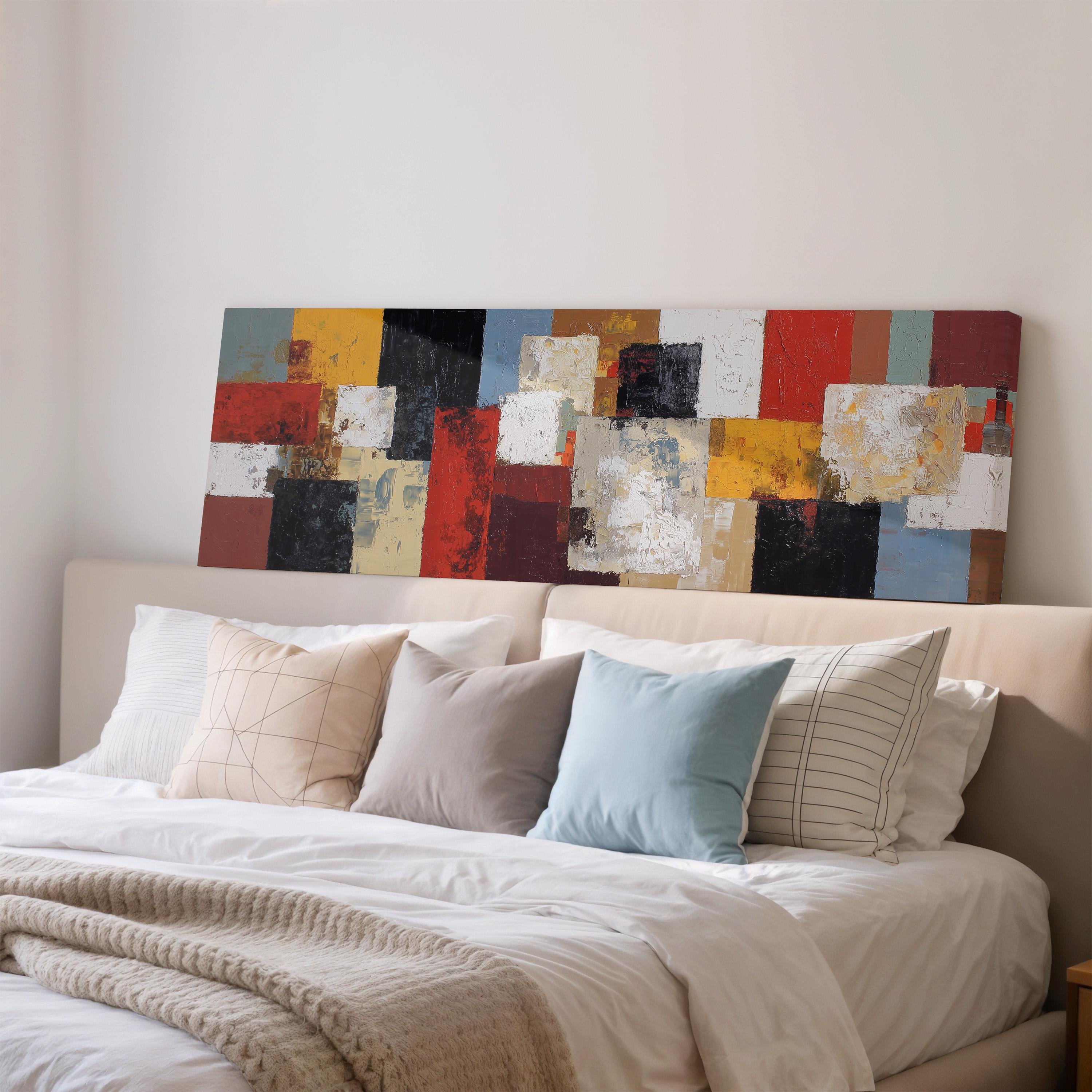 a large, colorful abstract painting displayed on a wall above a bed with white bedding and pillows.