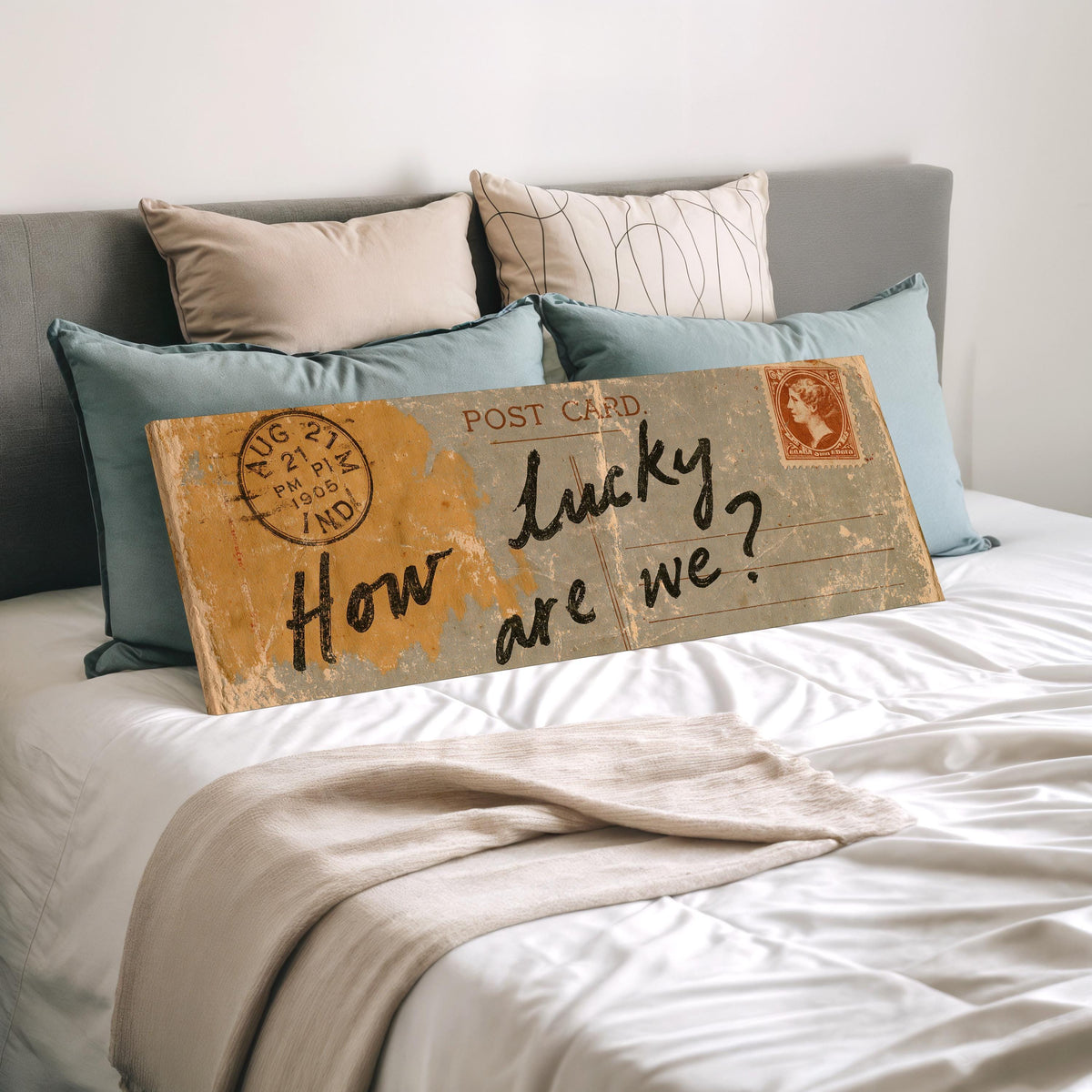 Vintage postcard saying how lucky are we wide panoramic canvas print laid on a bed to show its size