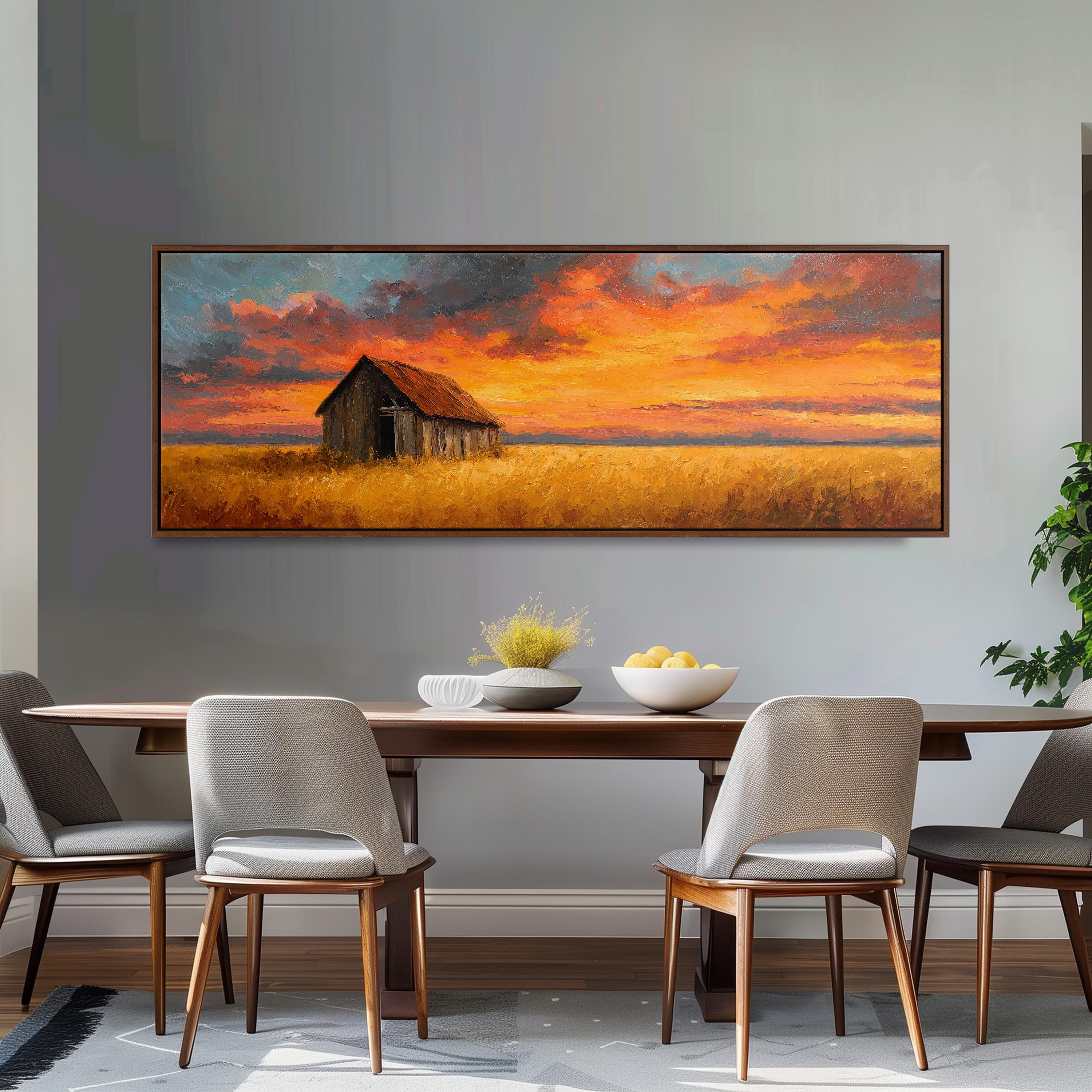 a large painting of a barn and a field with a colorful sunset sky above it, hanging on a wall above a wooden dining table with four chairs.