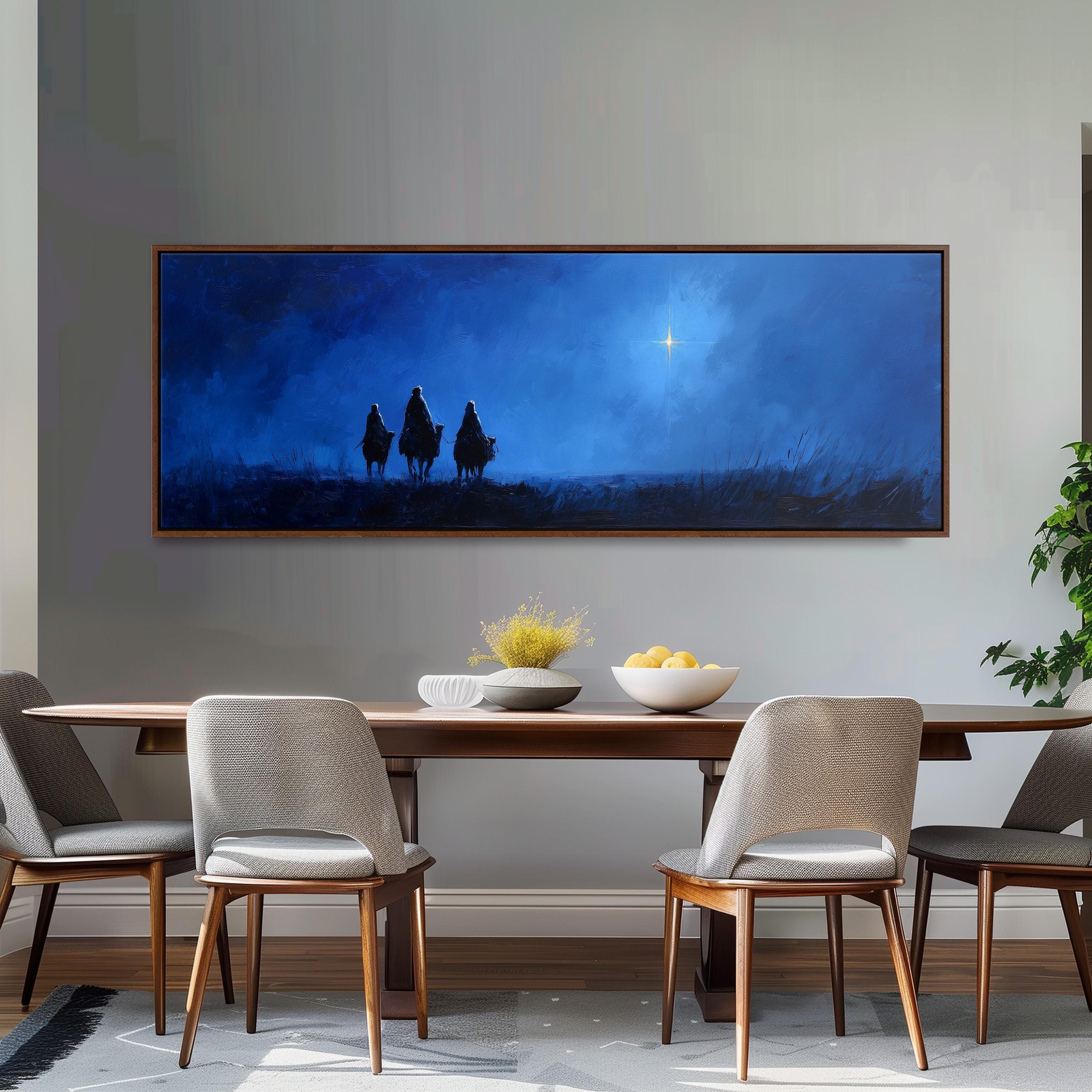 a large painting of three figures on a hill, with a star in the sky, hanging on a wall above a wooden dining table with four chairs.