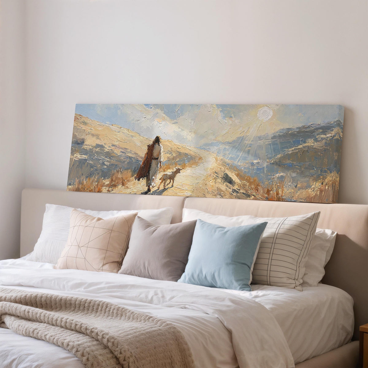 Jesus walking a sunlit hillside path with a sheep wide panoramic canvas print above a bed in a bedroom