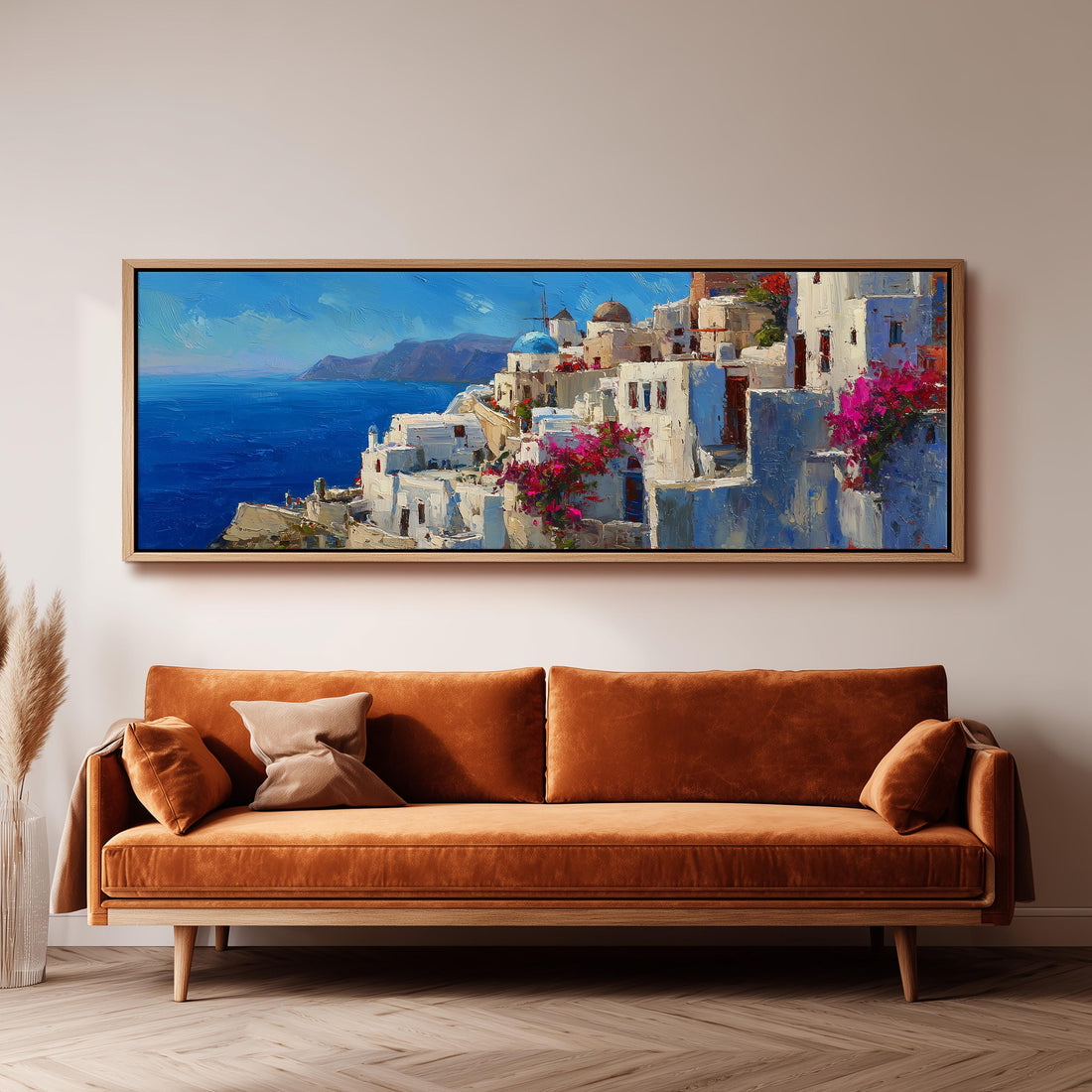 a large painting of a coastal town with white buildings and pink flowers hanging above a wooden dining table with four chairs.