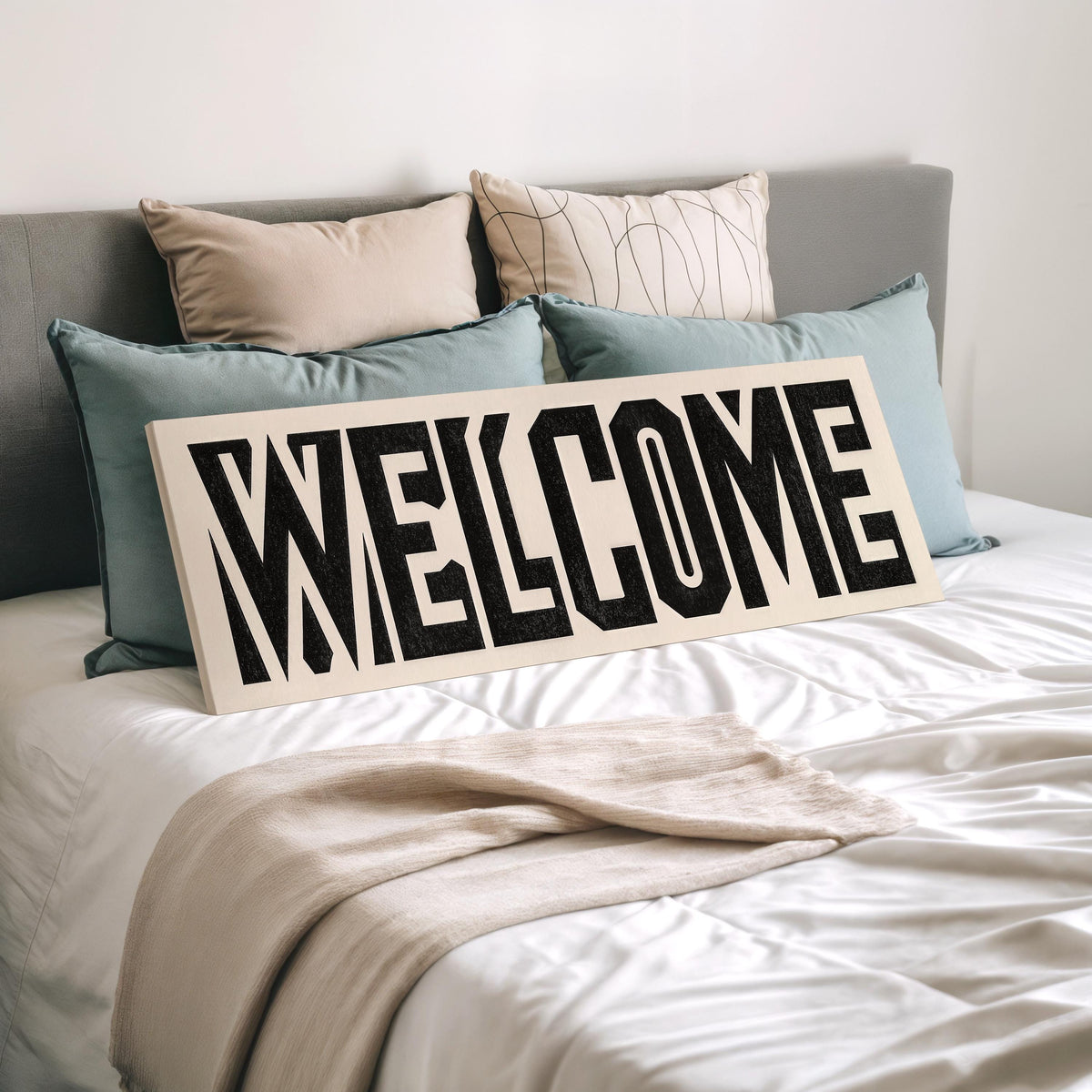 Bold welcome block letters wide panoramic canvas print laid on a bed to show its size