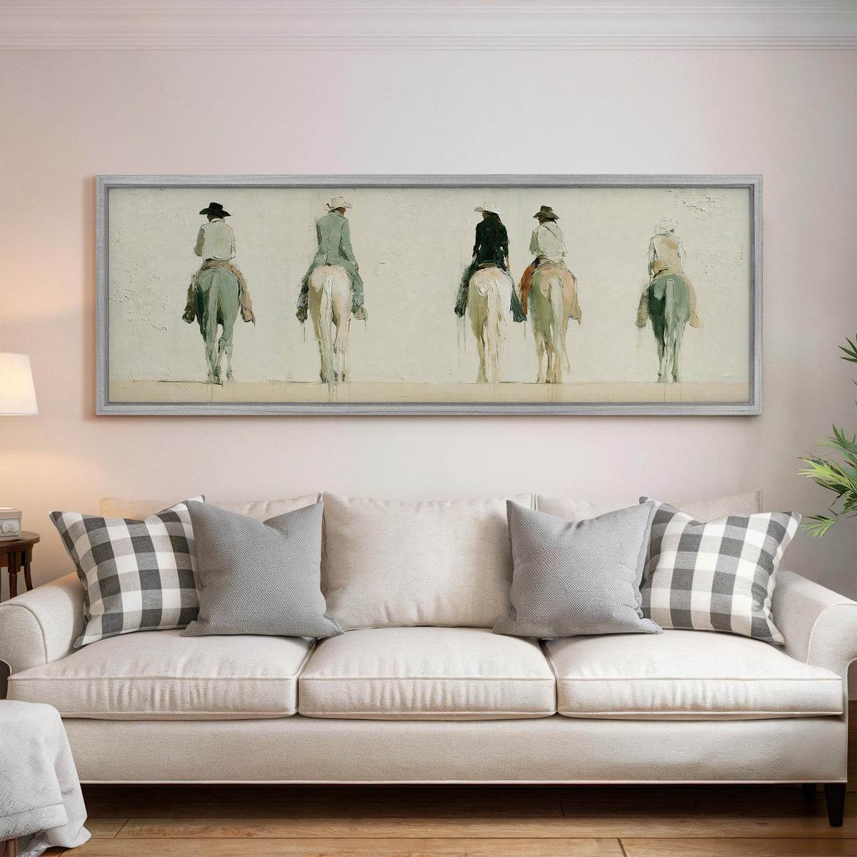 Riders on horseback seen from behind panoramic canvas print above a white sofa in a bright living room