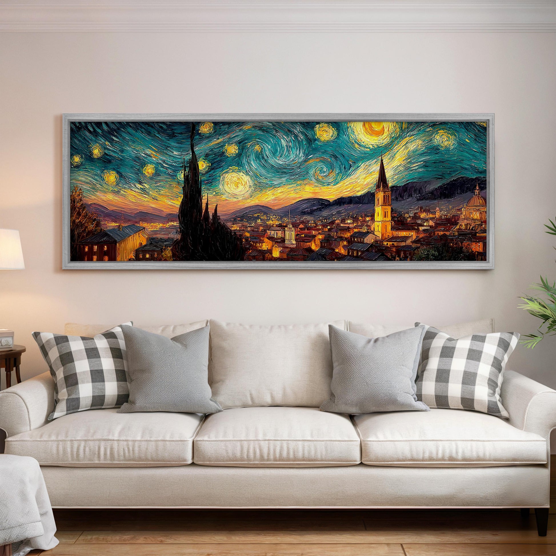 a large, framed painting of a cityscape with a starry night sky above, hanging on a wall above a white couch with patterned pillows.