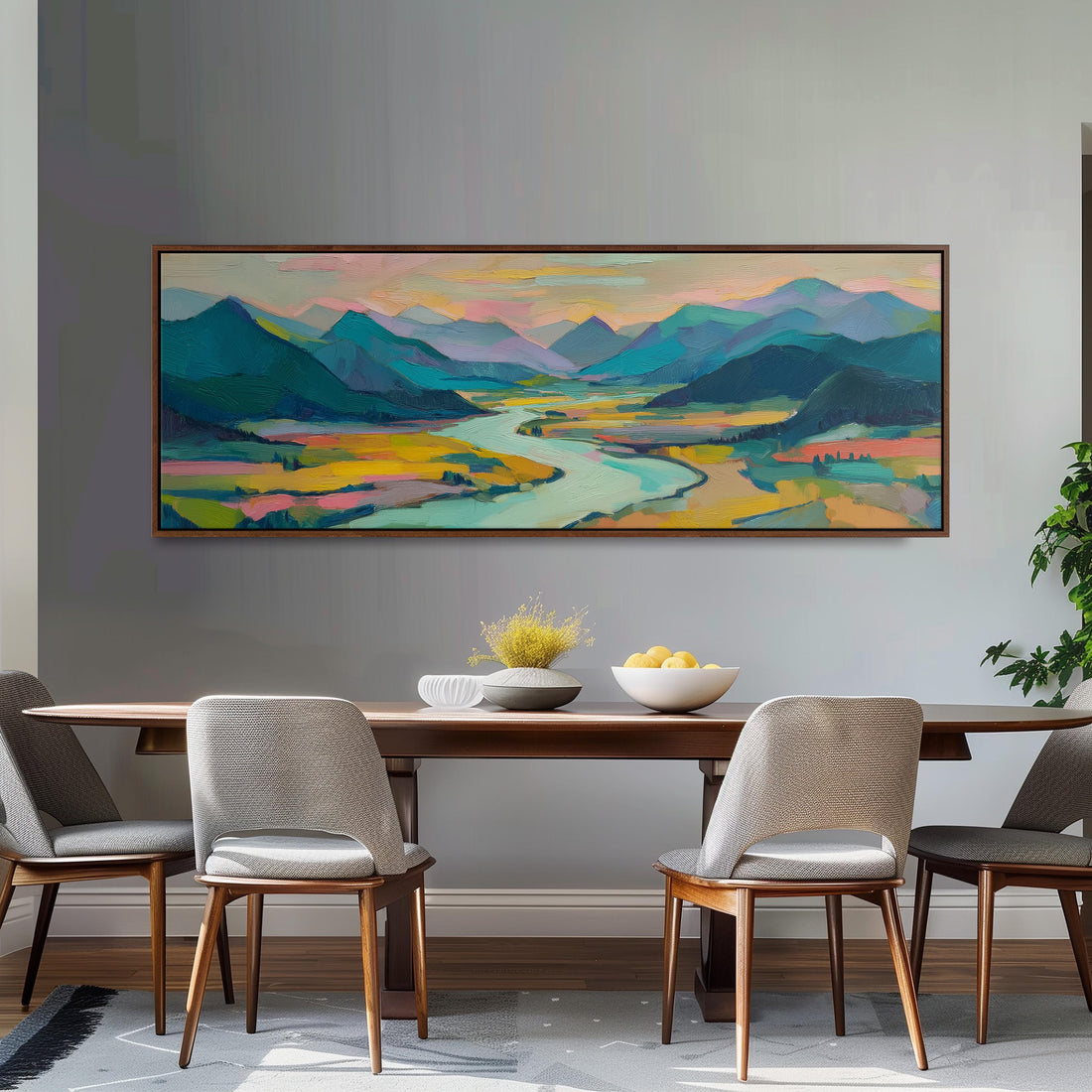 a large, colorful landscape painting hanging on a wall above a wooden dining table with four chairs. The painting depicts a scenic mountain range with a winding river, creating a serene and picturesque atmosphere.