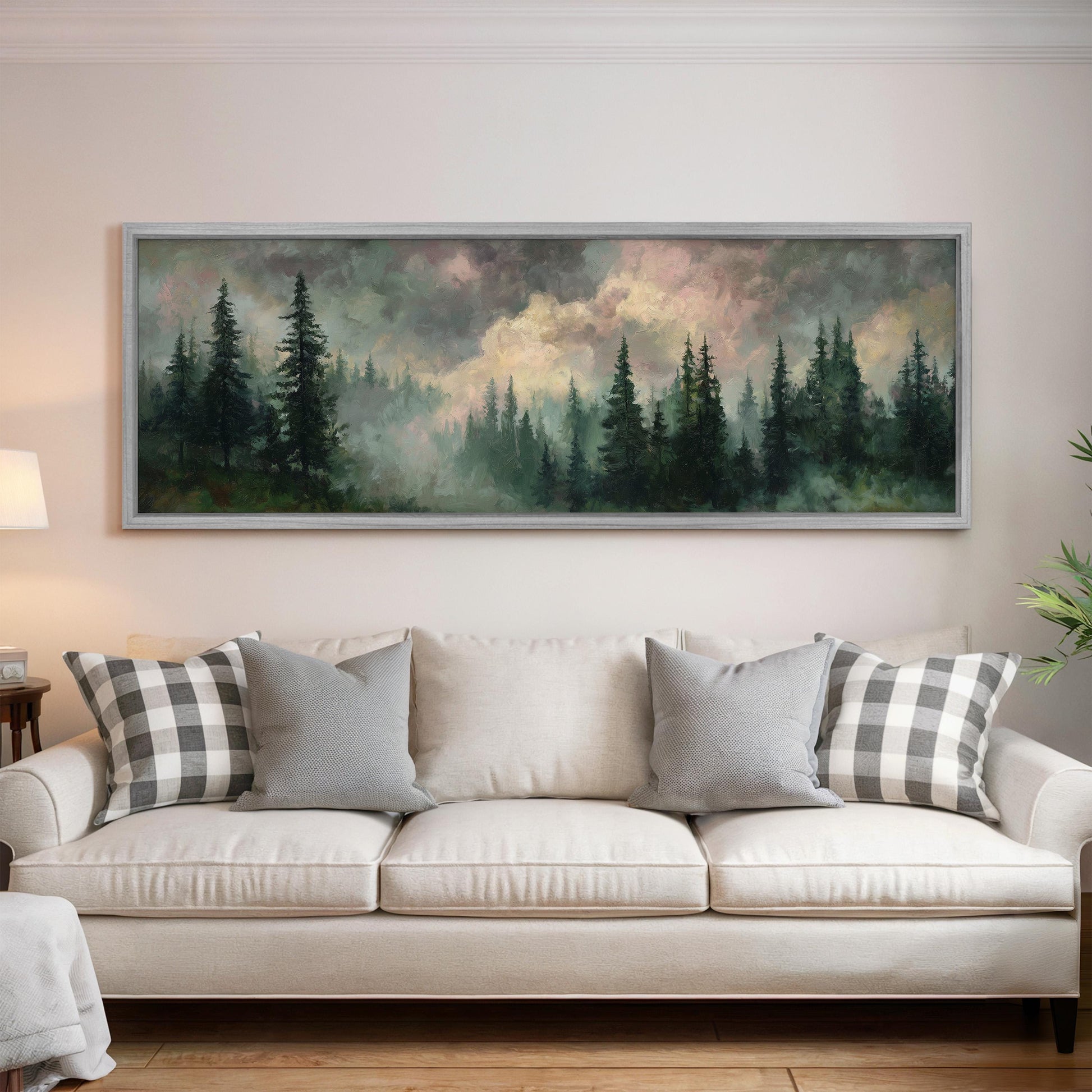 a large painting of a forest scene hanging on a wall above a white sofa with gray and white patterned pillows.