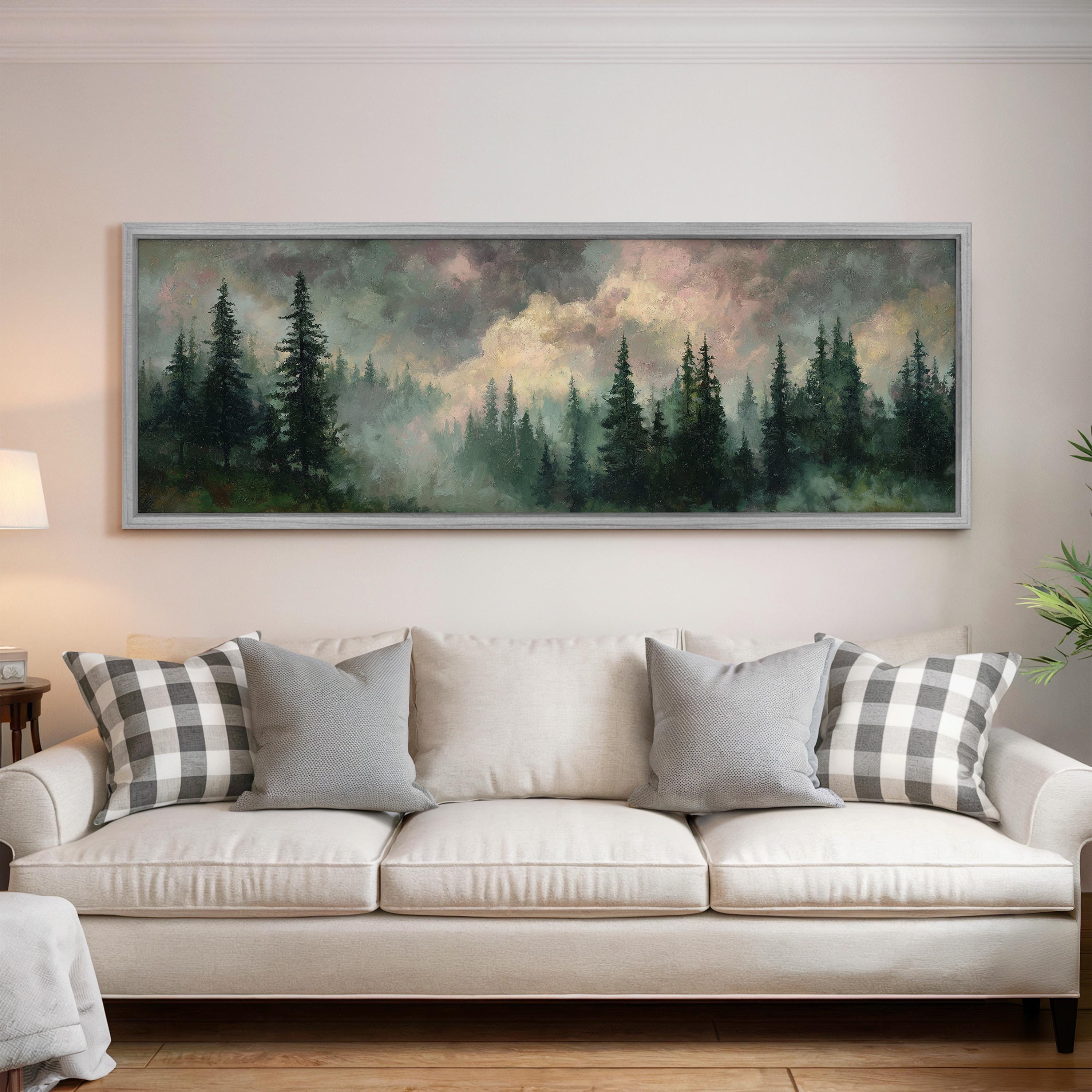 a large painting of a forest scene hanging on a wall above a white sofa with gray and white patterned pillows.