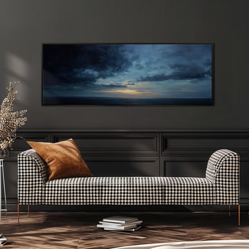 a modern living room with a black and white checkered sofa, a large framed painting of a stormy sky above the sofa, and a stack of books on the floor.