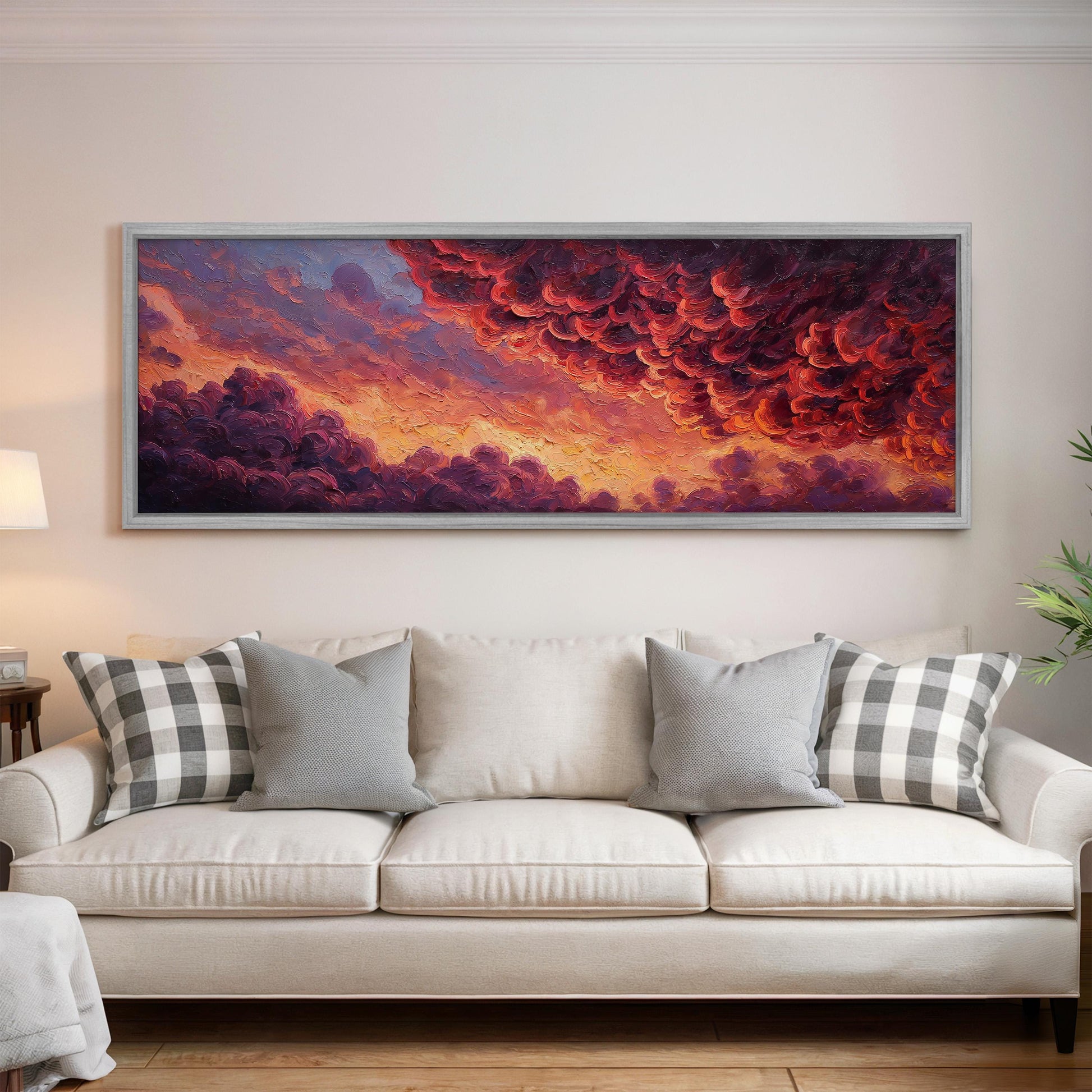 a large, framed painting of a dramatic sky with vibrant clouds hanging above a white couch in a living room setting.