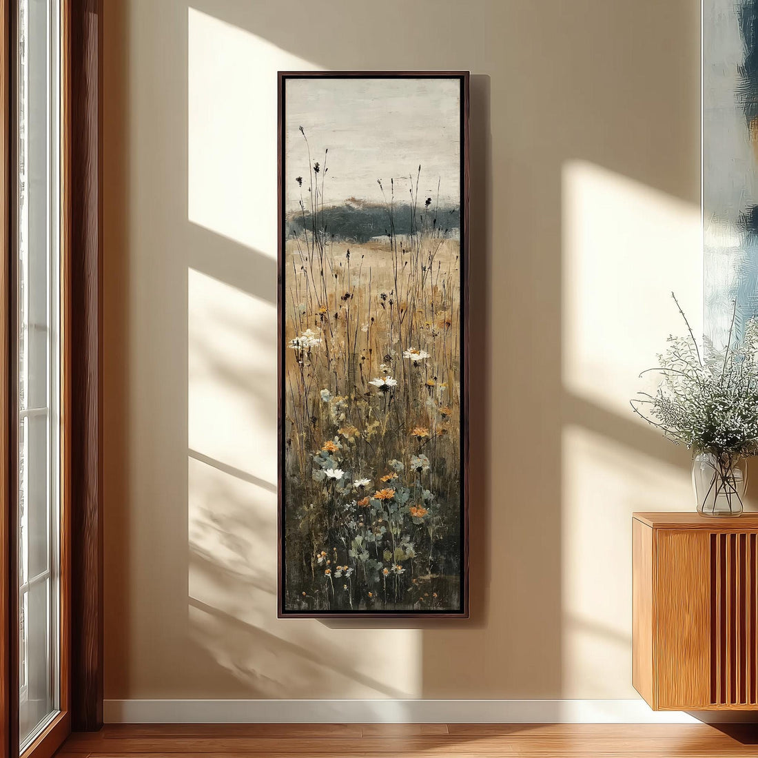 a large painting of a field with tall grass and wildflowers hanging on a wall in a room with wooden furniture.