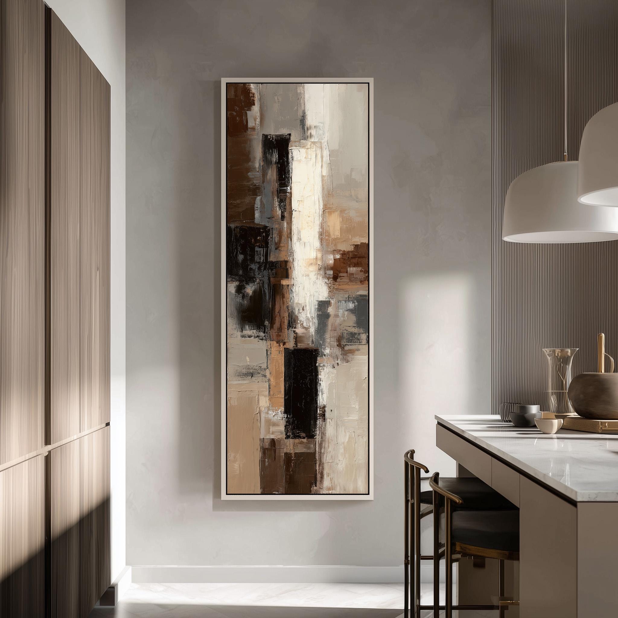 a modern kitchen with a large abstract painting hanging on the wall above a counter. The painting has a mix of brown, white, and black colors, creating a visually striking contrast. The kitchen is well-lit, with natural light coming in from a window on the left side of the image. The counter is equipped with a sink and a few decorative items, such as a vase and a bowl.
