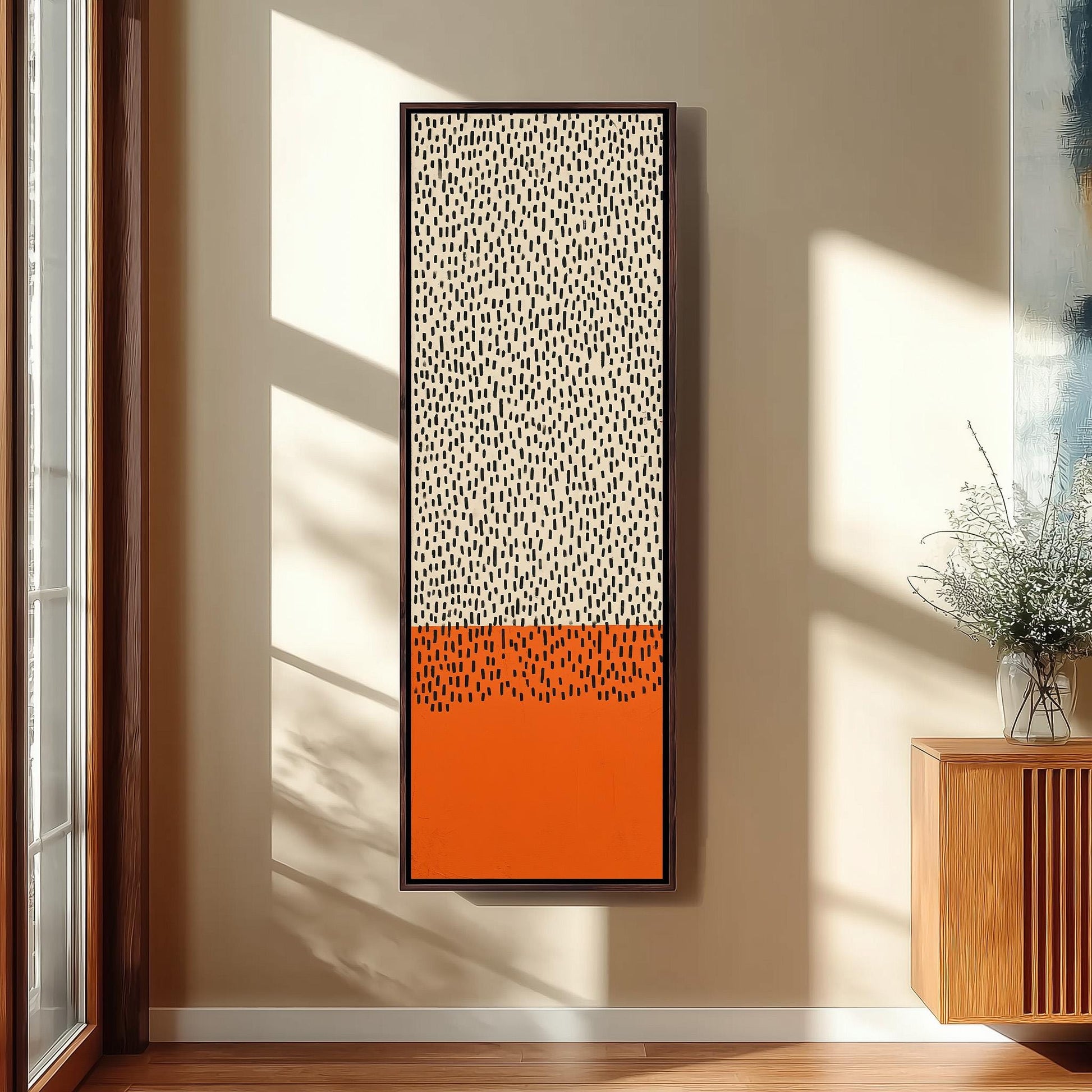 a large abstract painting hanging on a wall, with a wooden cabinet and a vase of flowers to the right of the painting.