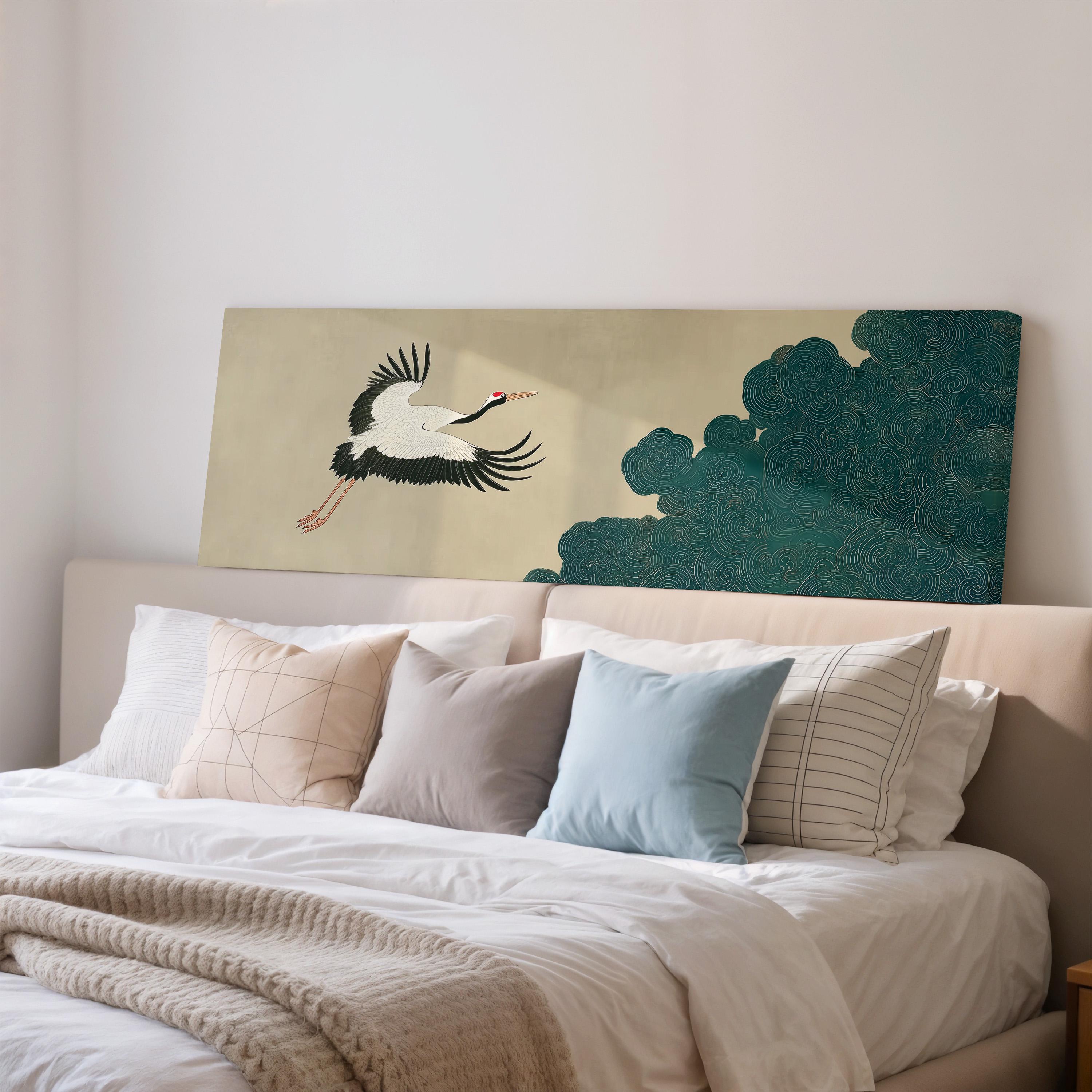 a large bed with a white comforter and various pillows, including a blue pillow and a striped pillow. Above the bed, there is a large painting or artwork depicting a crane in flight.