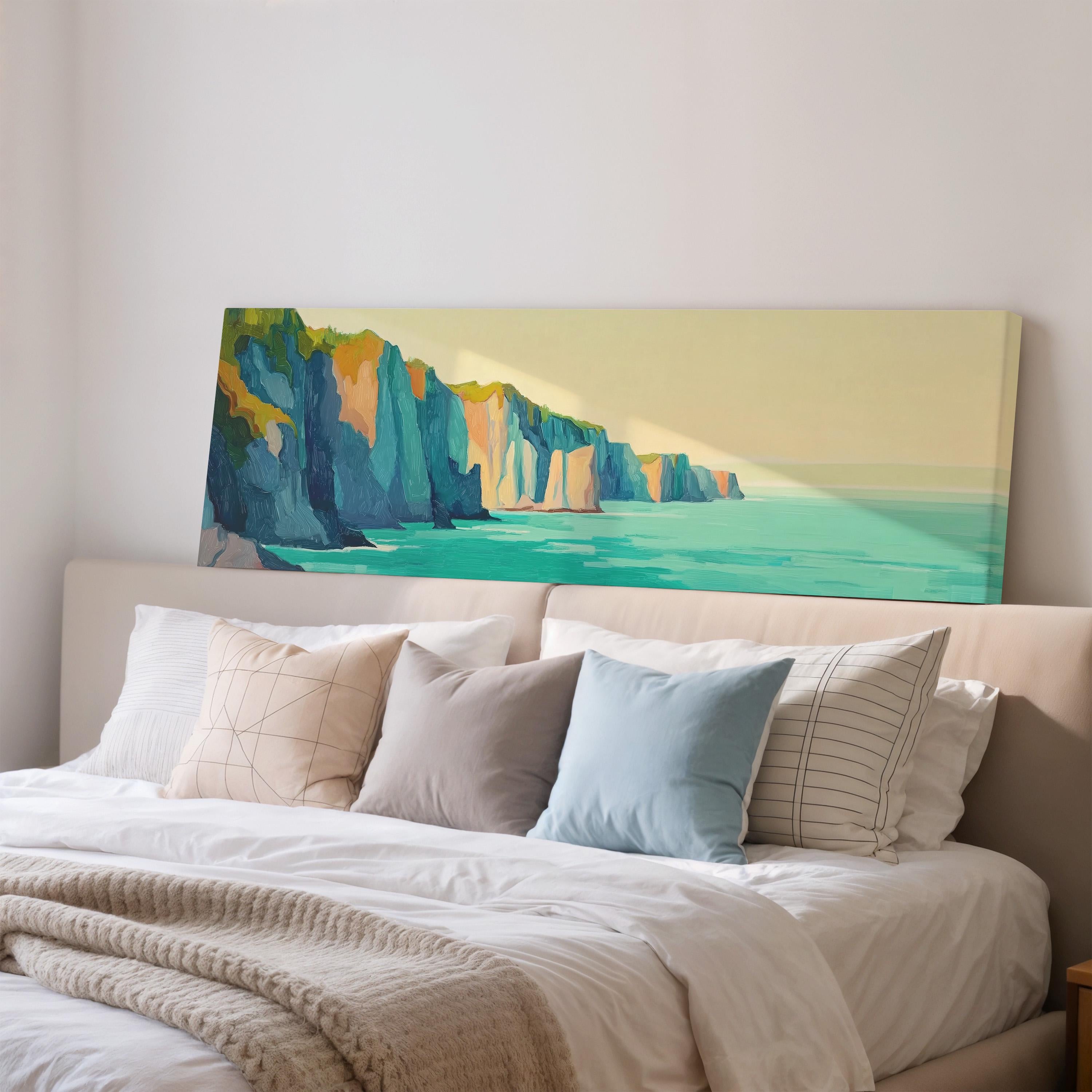 a large painting of a cliff overlooking the ocean, which is displayed on the wall above a bed with white pillows and a gray blanket.