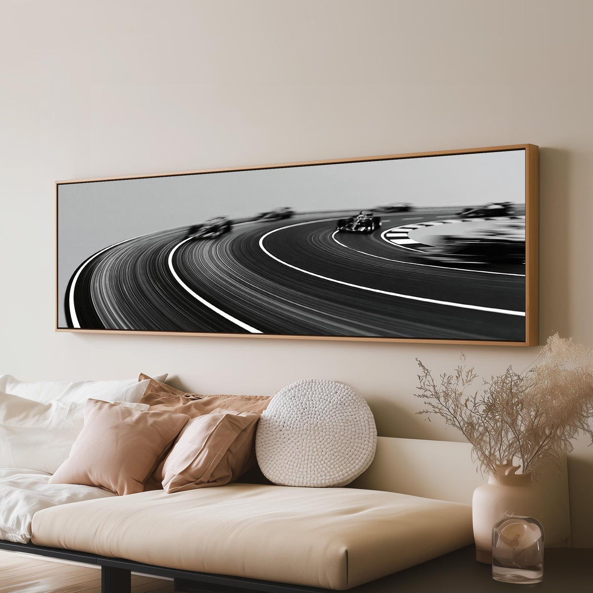 Race cars sweeping around a curve in black and white panoramic canvas print above a sofa in a living room