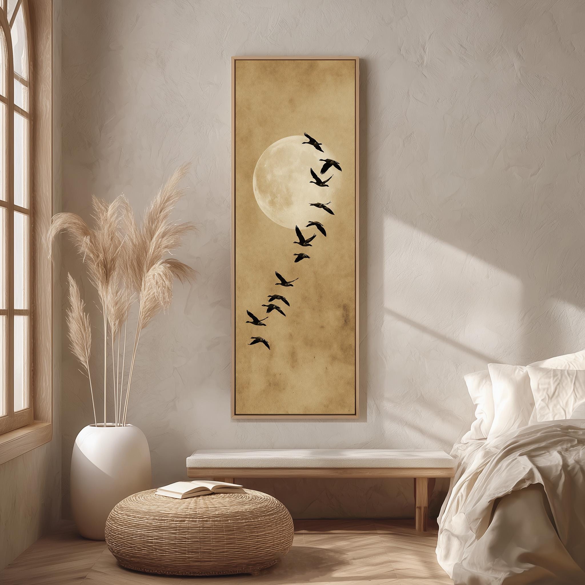 a serene bedroom scene with a large framed artwork of a flock of birds against a moon backdrop, a white bed with a white pillow, a white vase with tall potted plants, and a woven ottoman.