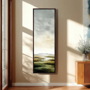 a large, rectangular painting hanging on a wall, depicting a serene landscape with a body of water and a sky with clouds.