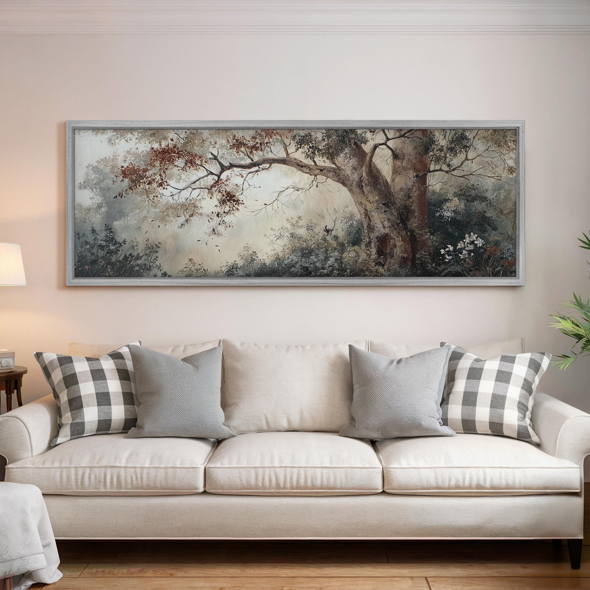 a large, framed painting of a tree with autumn foliage hanging on a wall above a white sofa with gray and white plaid throw pillows.