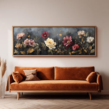 a large, framed painting of flowers hanging on a wall above a brown sofa.