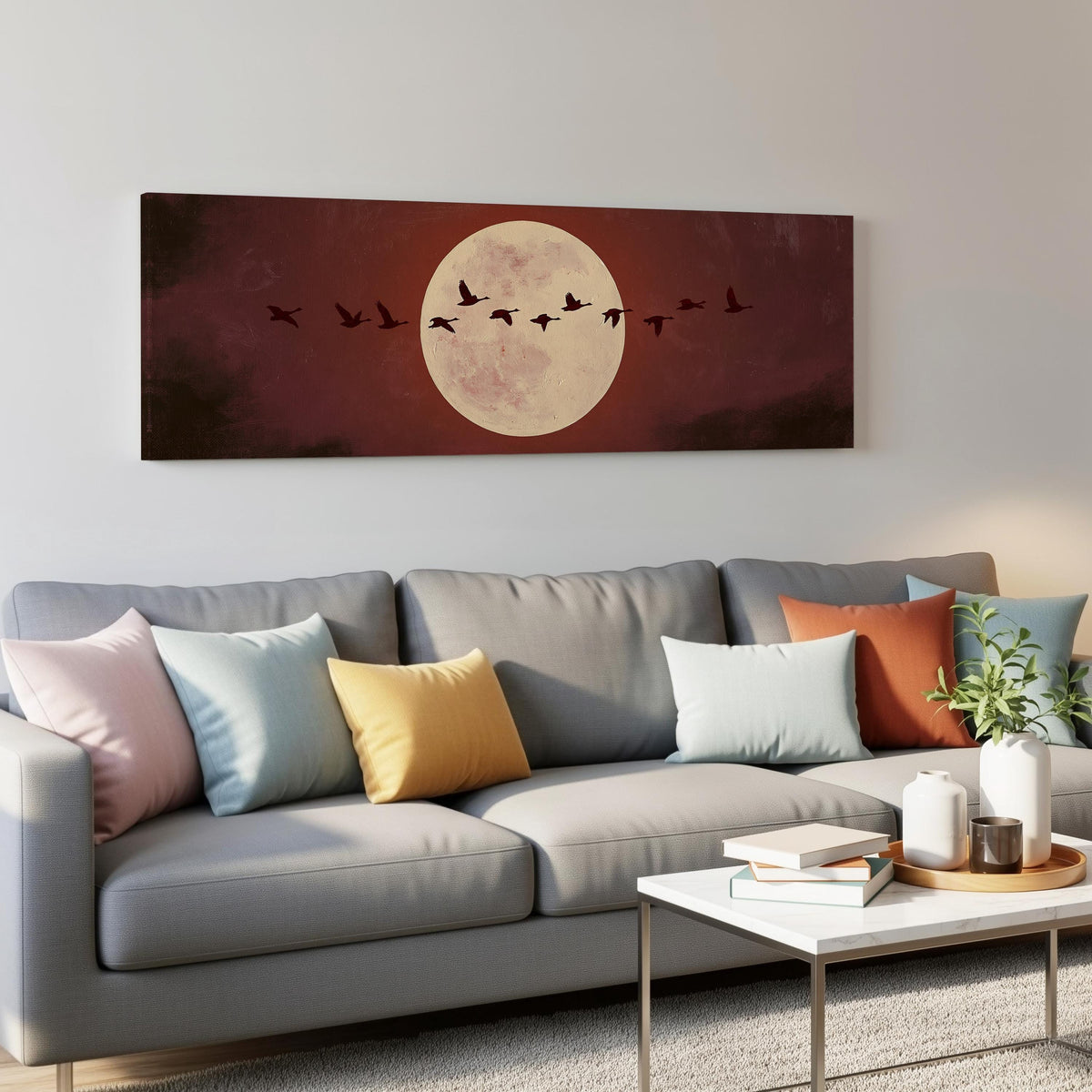 Geese crossing a pale moon on maroon panoramic canvas print above a grey sofa in a living room