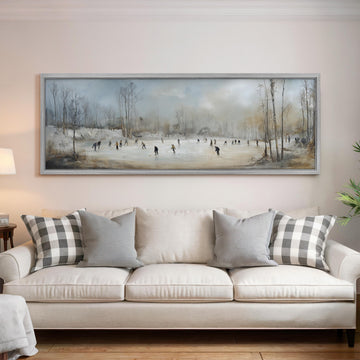 a large painting of people ice skating on a frozen pond, hanging on a wall above a white sofa with gray and white patterned pillows.